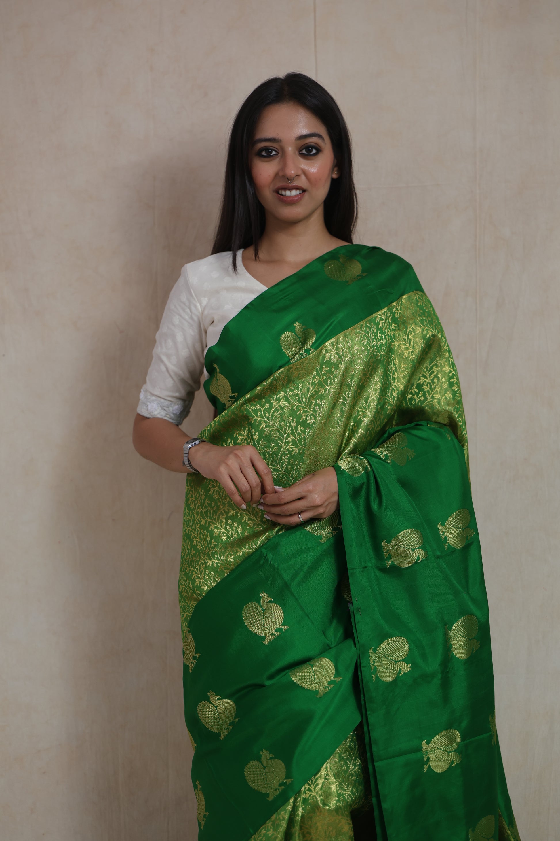 Front drape view of emerald green Kanjivaram silk saree with traditional peacock buttas and brocade detailing