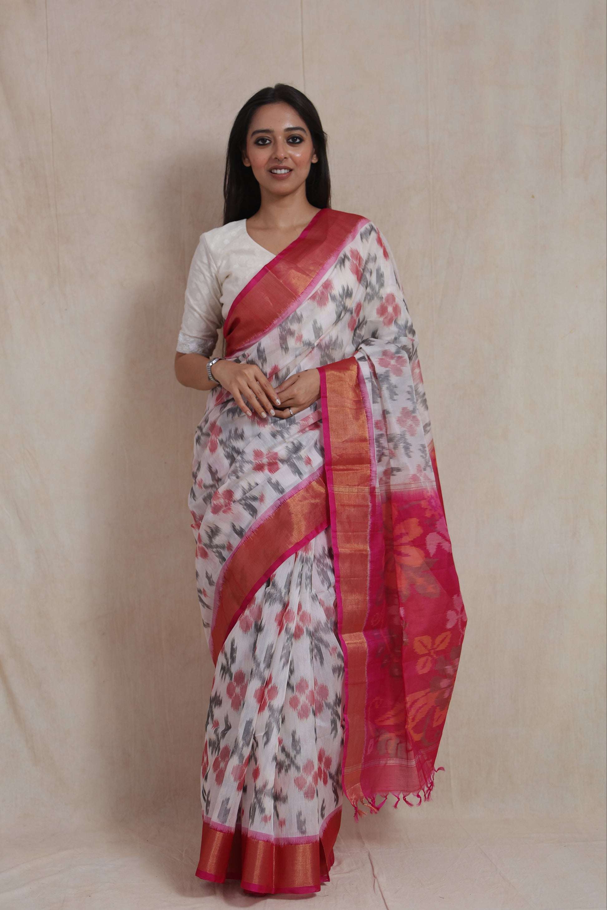 Full-length view of ivory Pochampally silk cotton saree showcasing floral motifs, pink border, and elegant drape