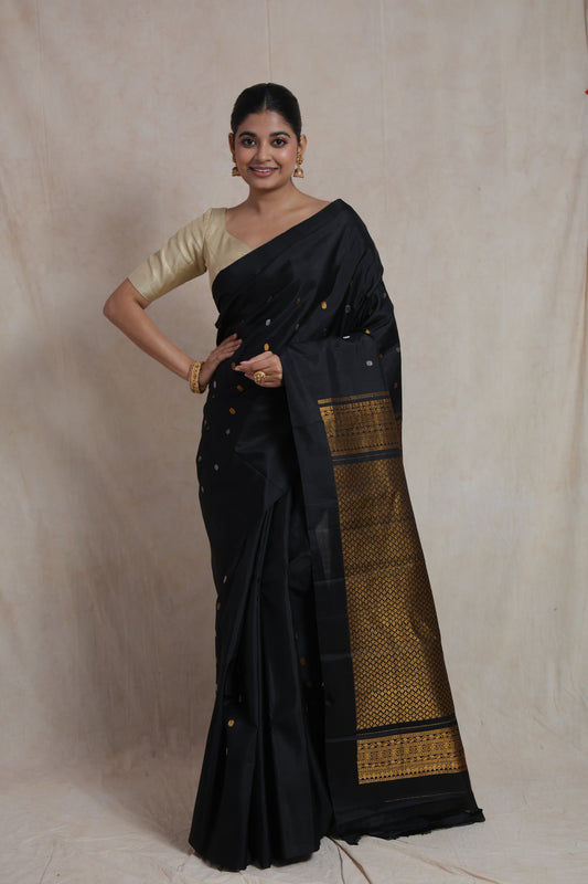 Model wearing black Gadwal silk saree with woven gold pallu