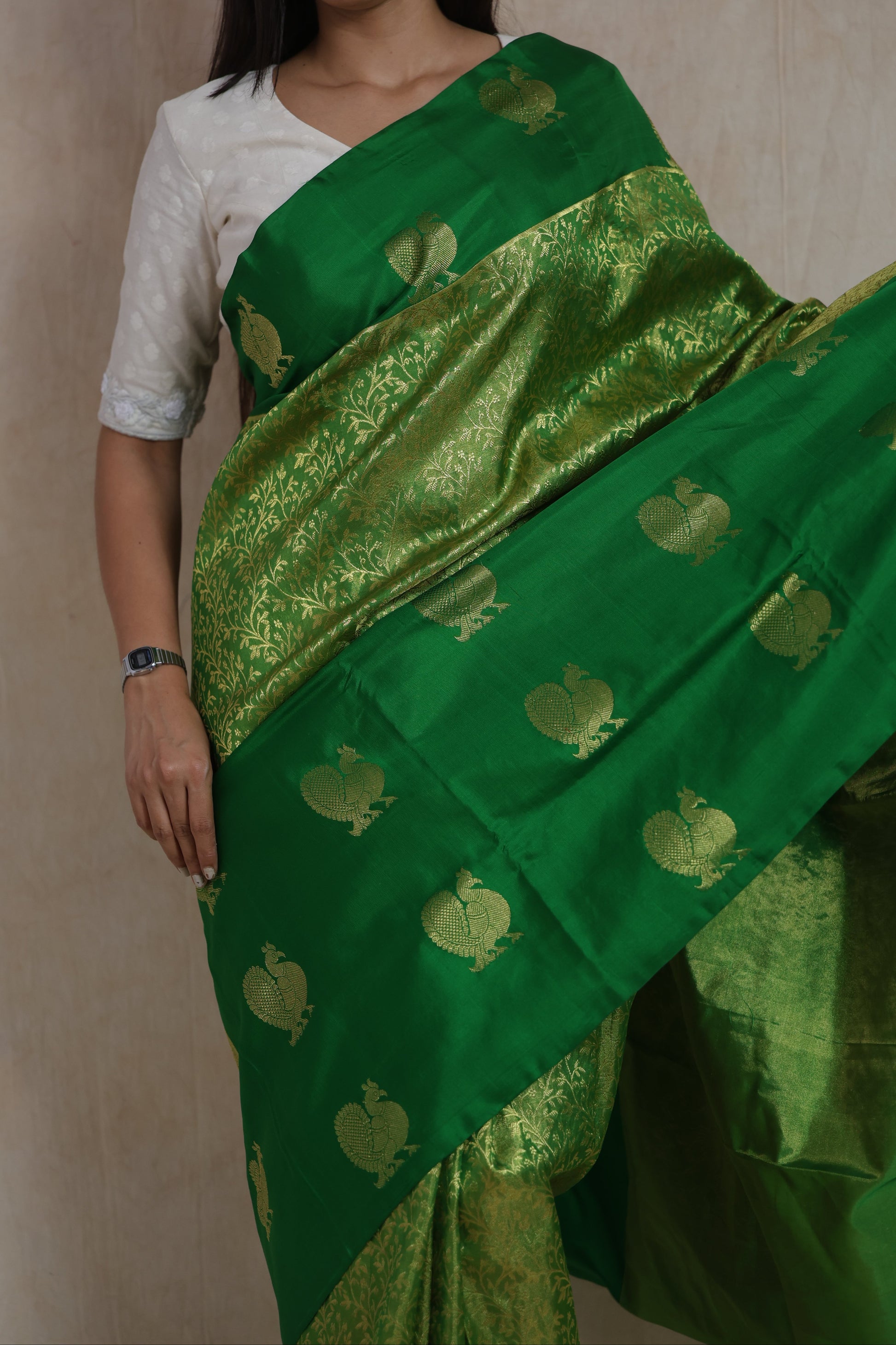 Close-up of emerald green Kanjivaram silk saree with peacock buttas and intricate woven floral patterns