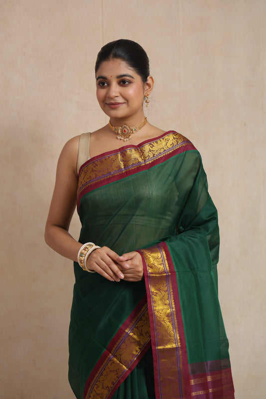 Close-up of emerald green Kanchipuram SICO saree showcasing the rich purple woven border and elegant craftsmanship