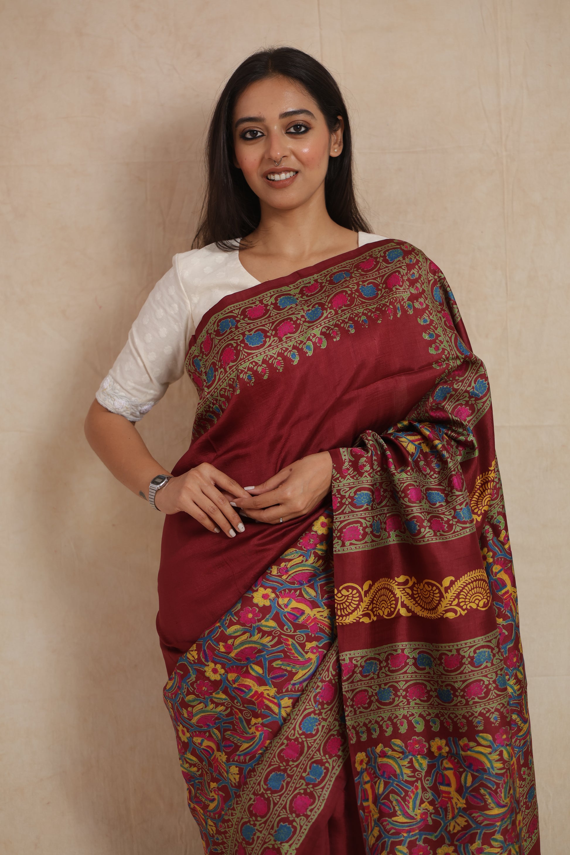 Model wearing deep maroon Batik silk saree with artistic floral and bird motif patterns