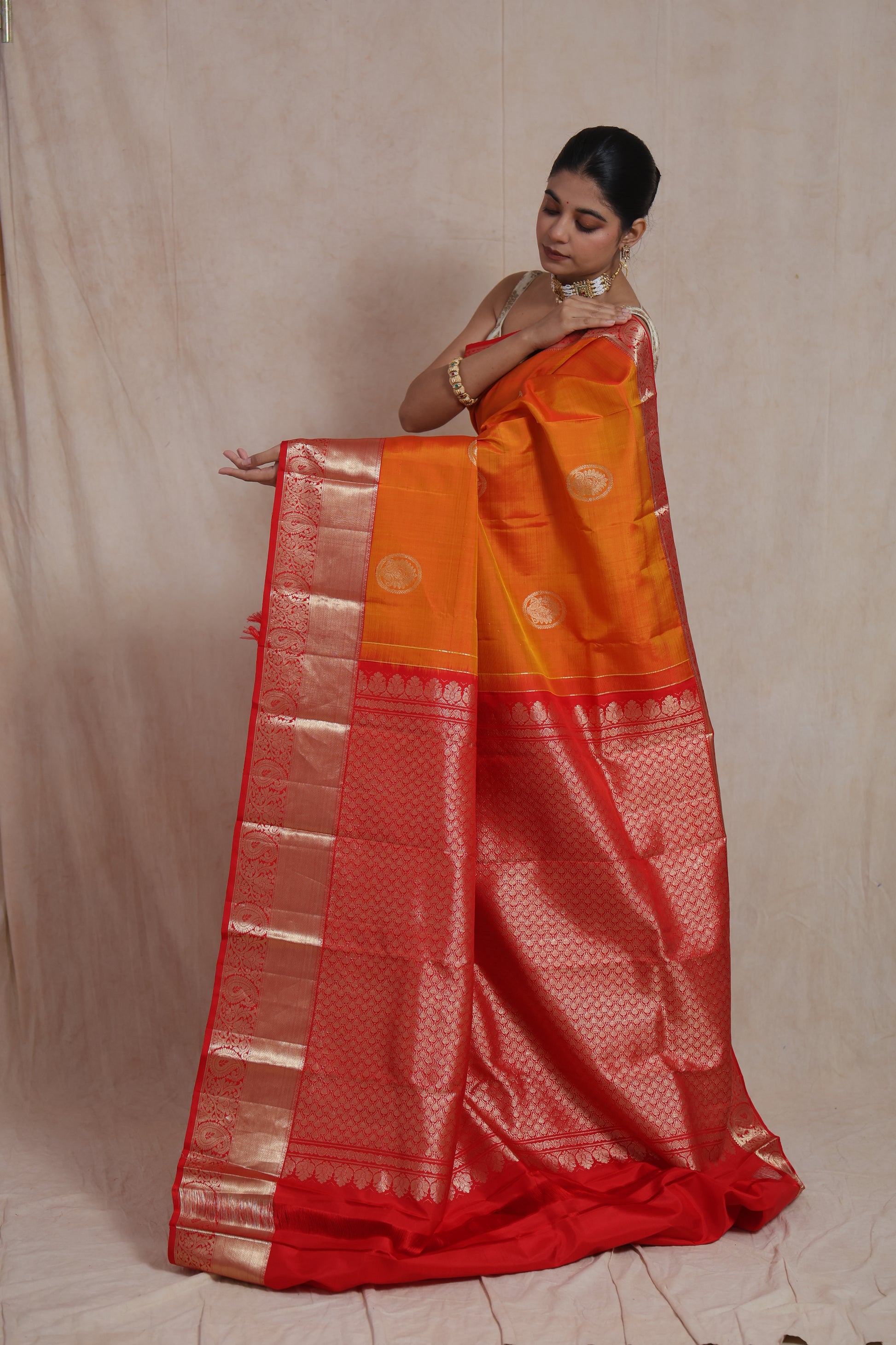 Side pose of handcrafted orange Kanjivaram silk saree with woven zari border