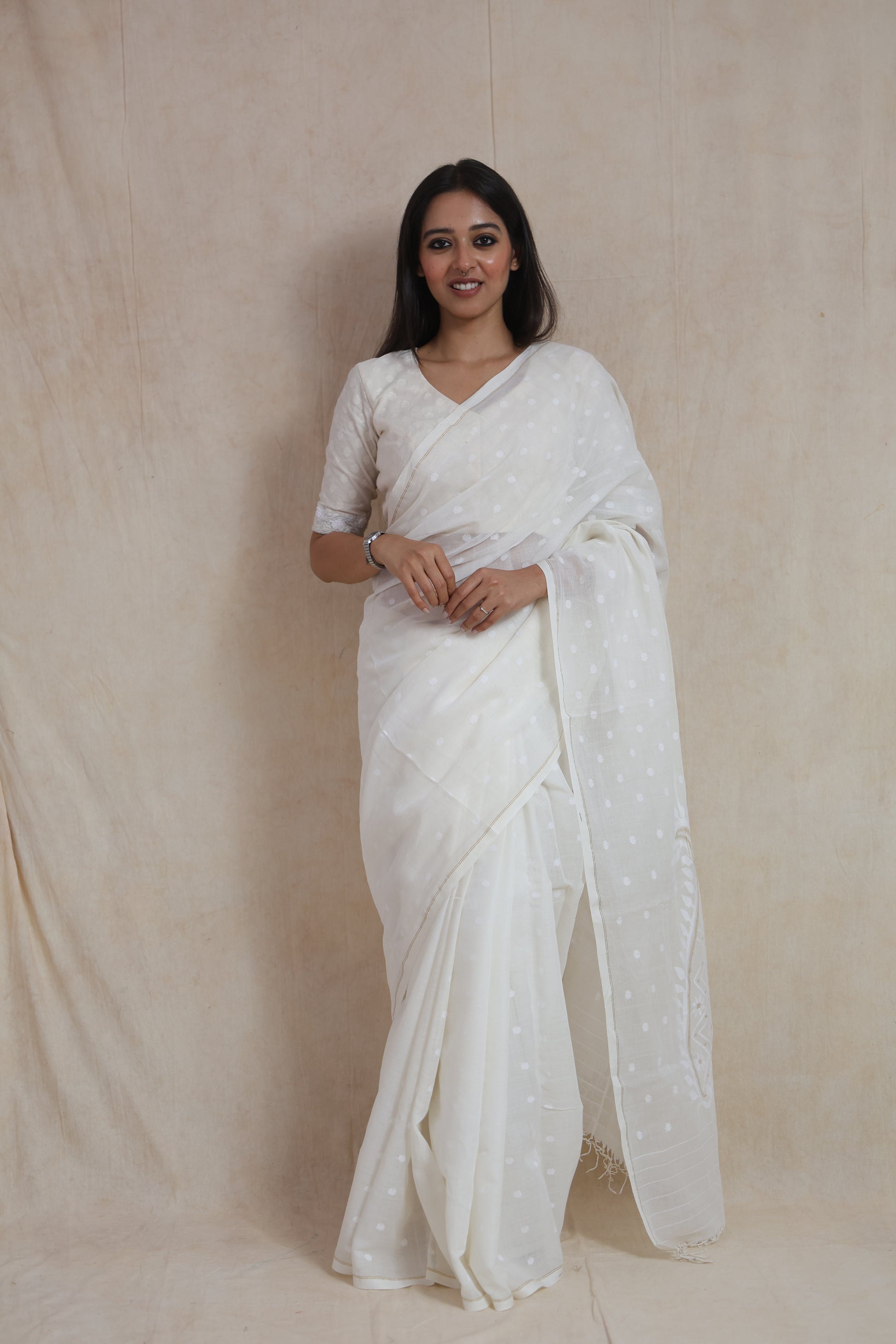 Portrait view of model wearing elegant off-white Bengal Fulia cotton saree with minimal woven detailing