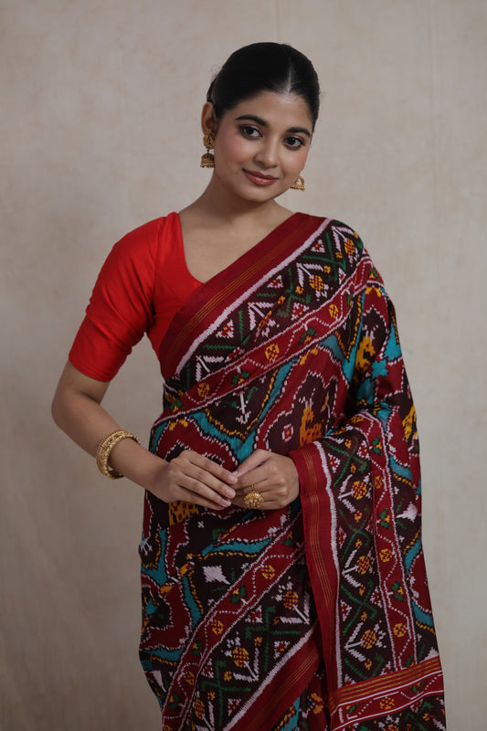 Front drape view of maroon Patola handloom silk saree featuring traditional ikat motifs and artisanal craftsmanship