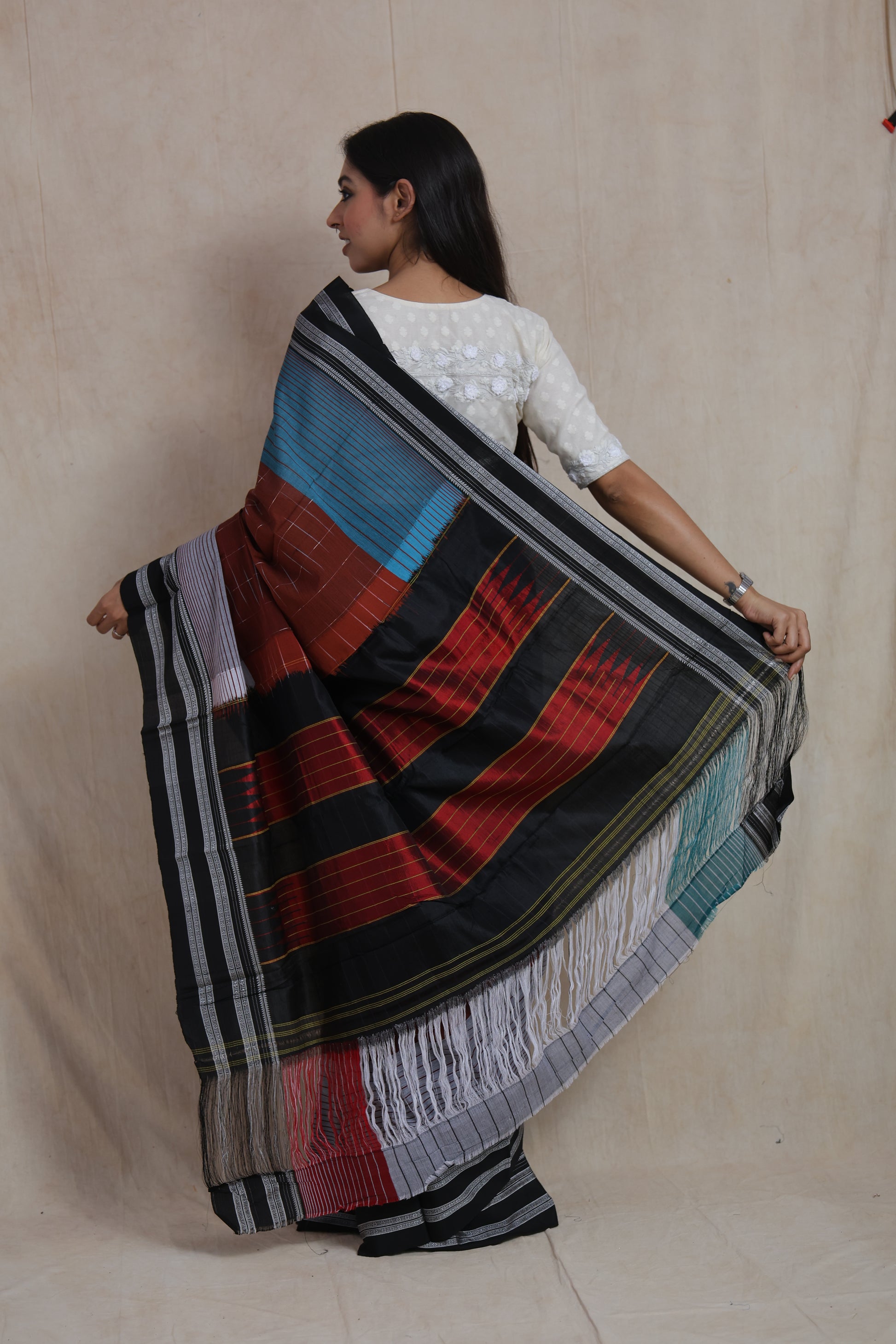 Back pallu view of rust brown and teal Ilak cotton saree with bold woven design