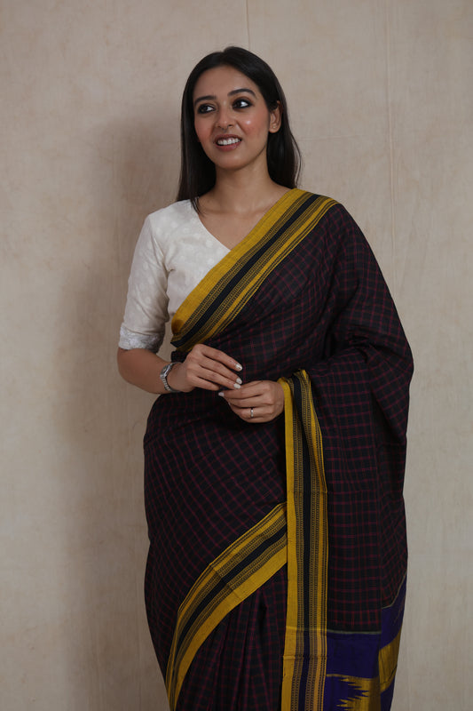 Closeup of black Ilak cotton saree featuring fine red checks and mustard border