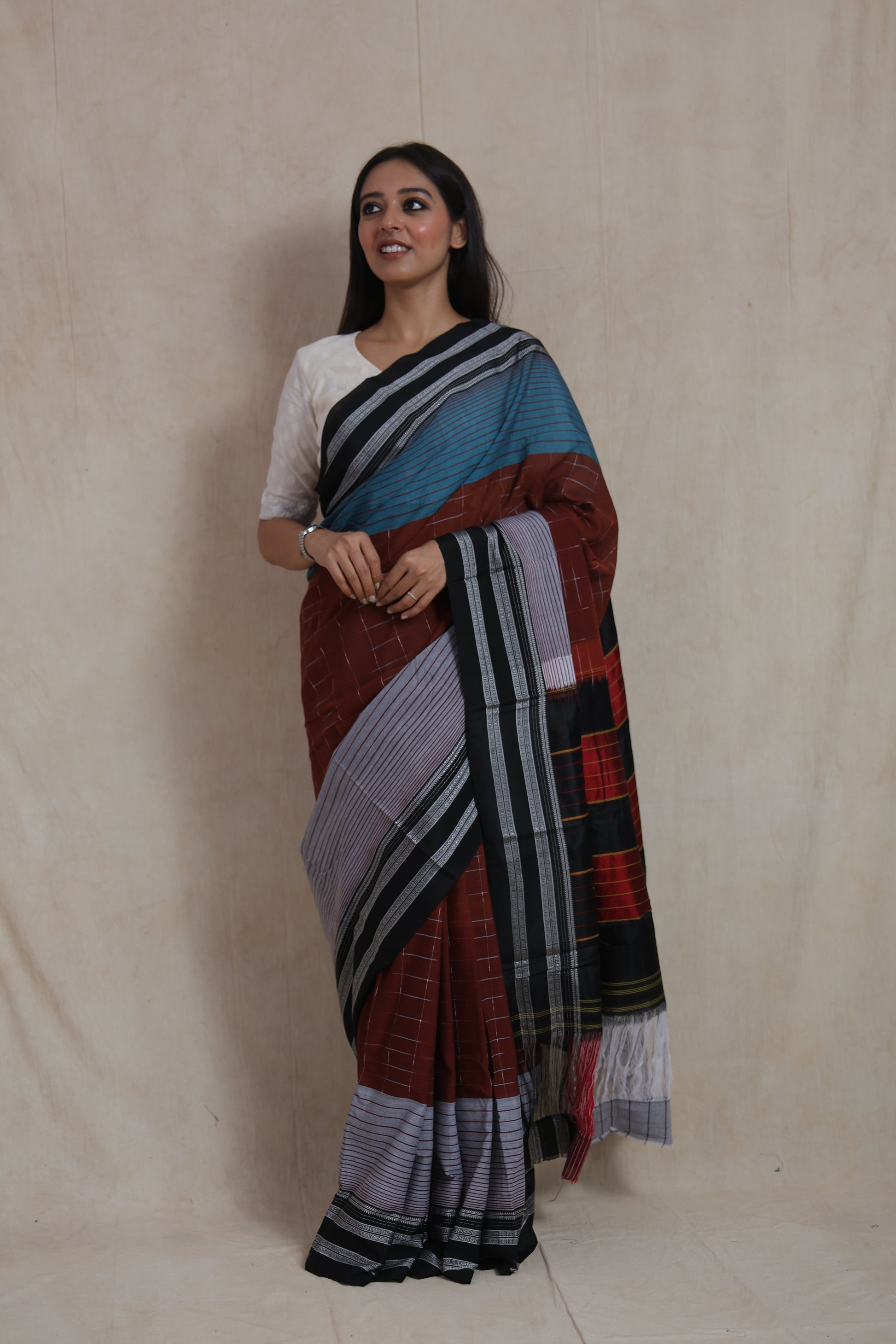 Elegant front drape of rust brown and teal Ilak cotton saree with woven stripes