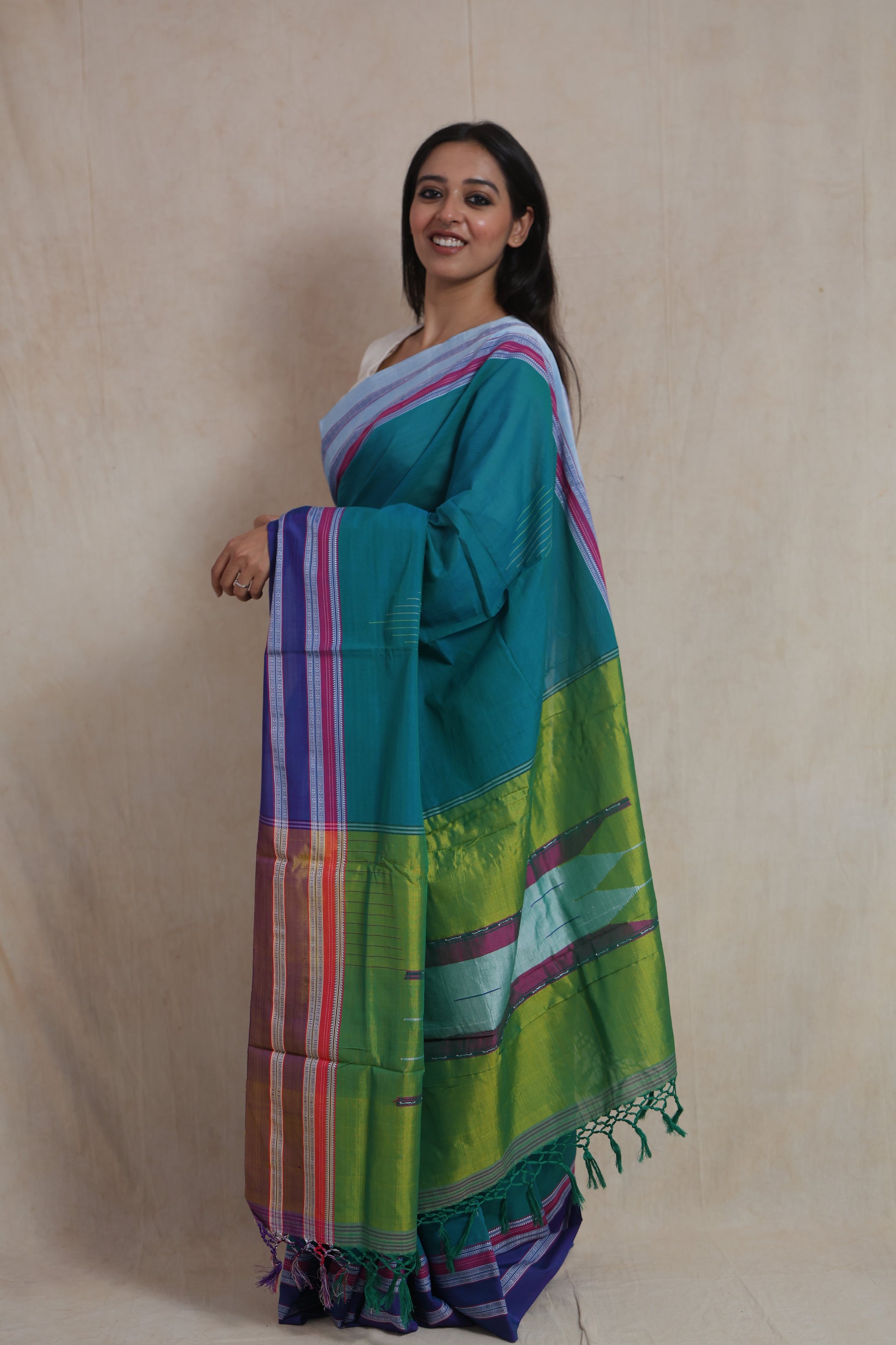 Side standing pose showcasing the contrast pallu of teal green Ilkal saree