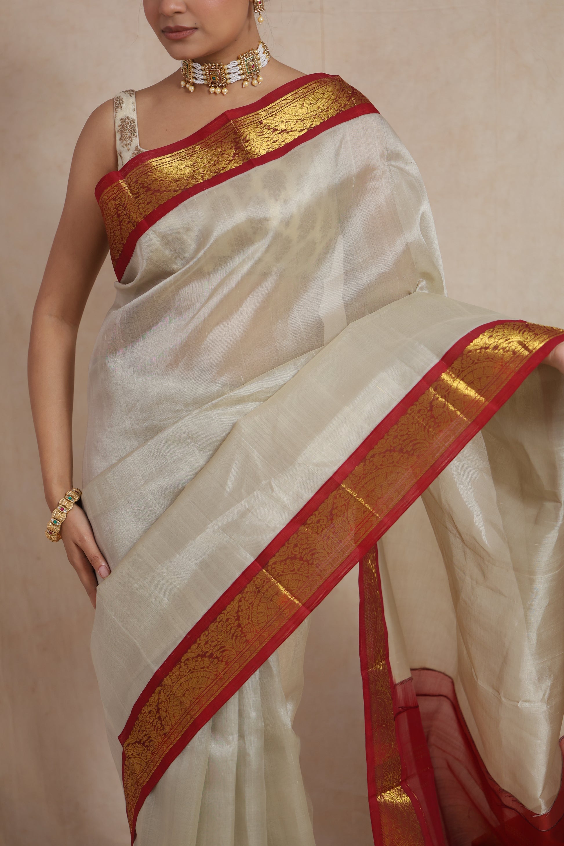Back drape view of ivory Kanchipuram Sico saree with traditional red pallu