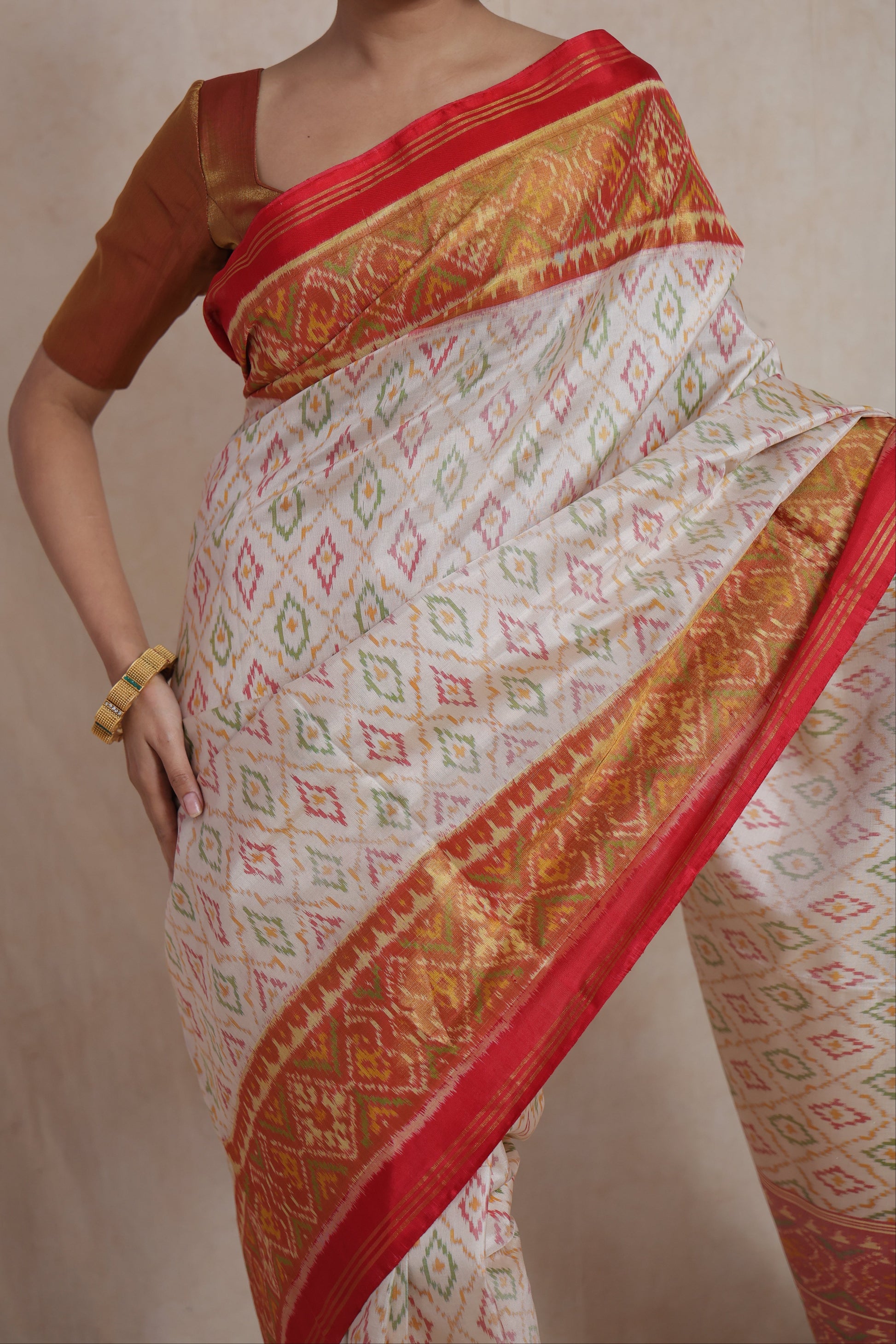 Close-up of ivory white Patola silk saree featuring multicolour geometric motifs and red woven border