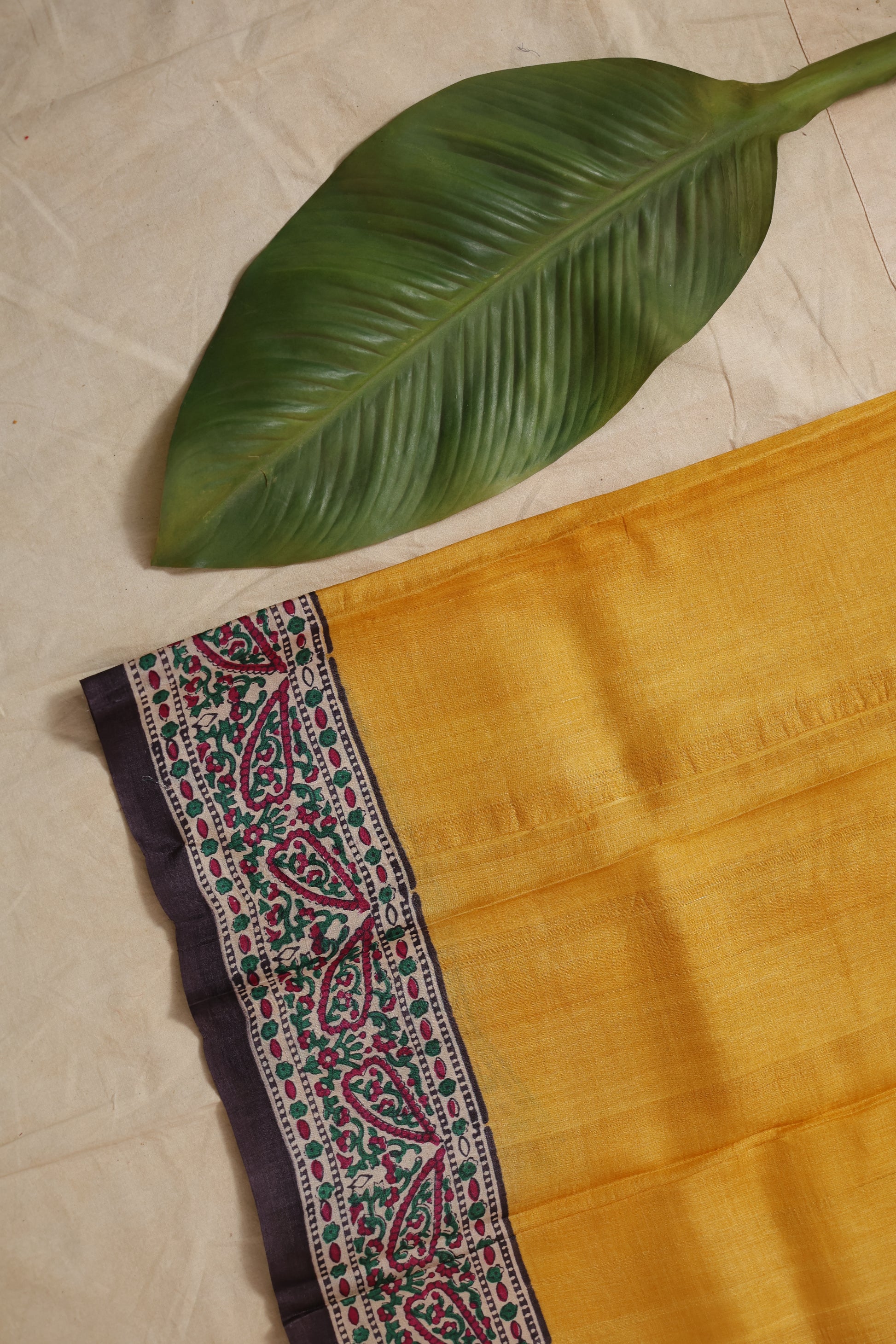 Flatlay view of ivory Tussar print saree with multicolor paisley border