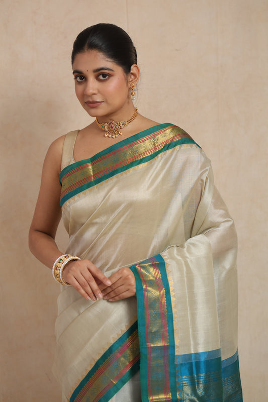 Model wearing ivory white Kanchipuram Sico saree with teal blue traditional border