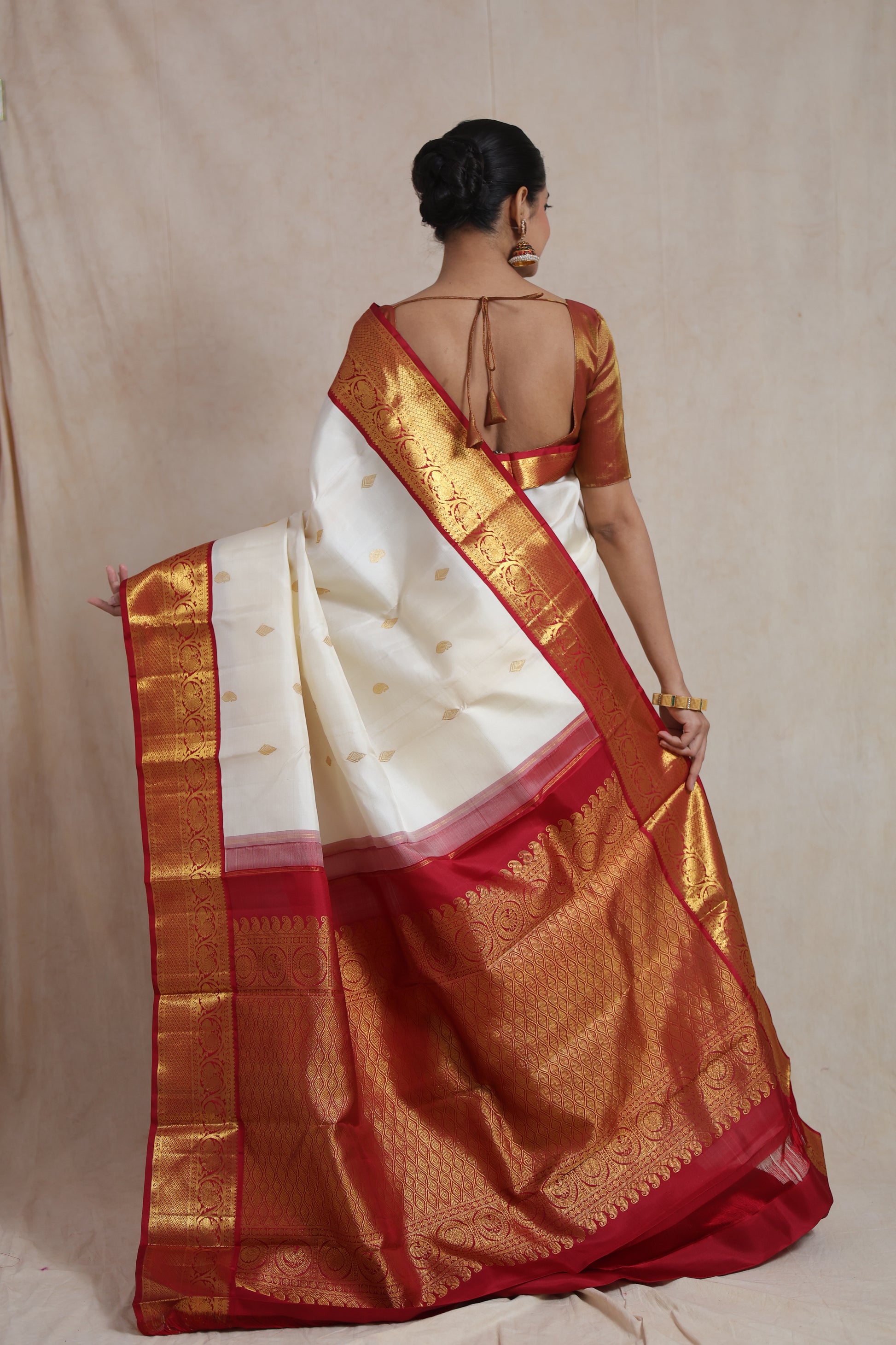 Back view of ivory white Kanjivaram pure silk saree showcasing richly woven red pallu and traditional border
