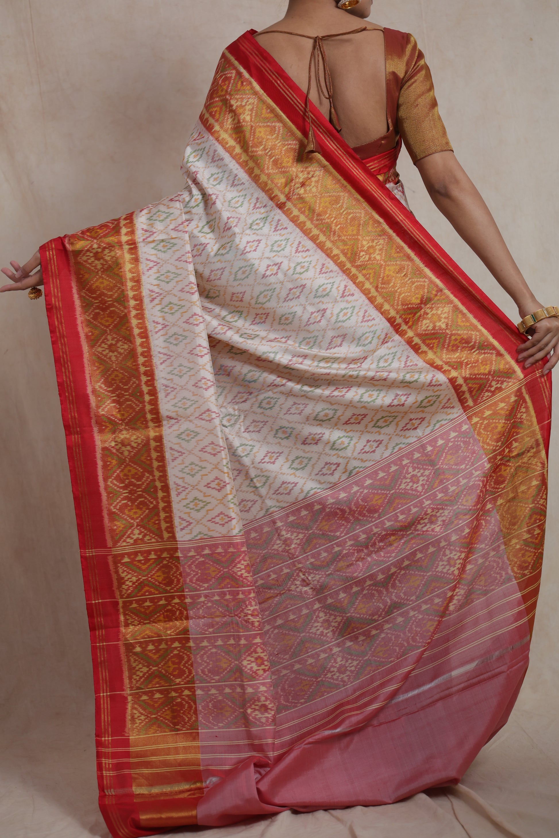 Back view of ivory white Patola handloom silk saree with crimson red woven pallu and traditional geometric motifs
