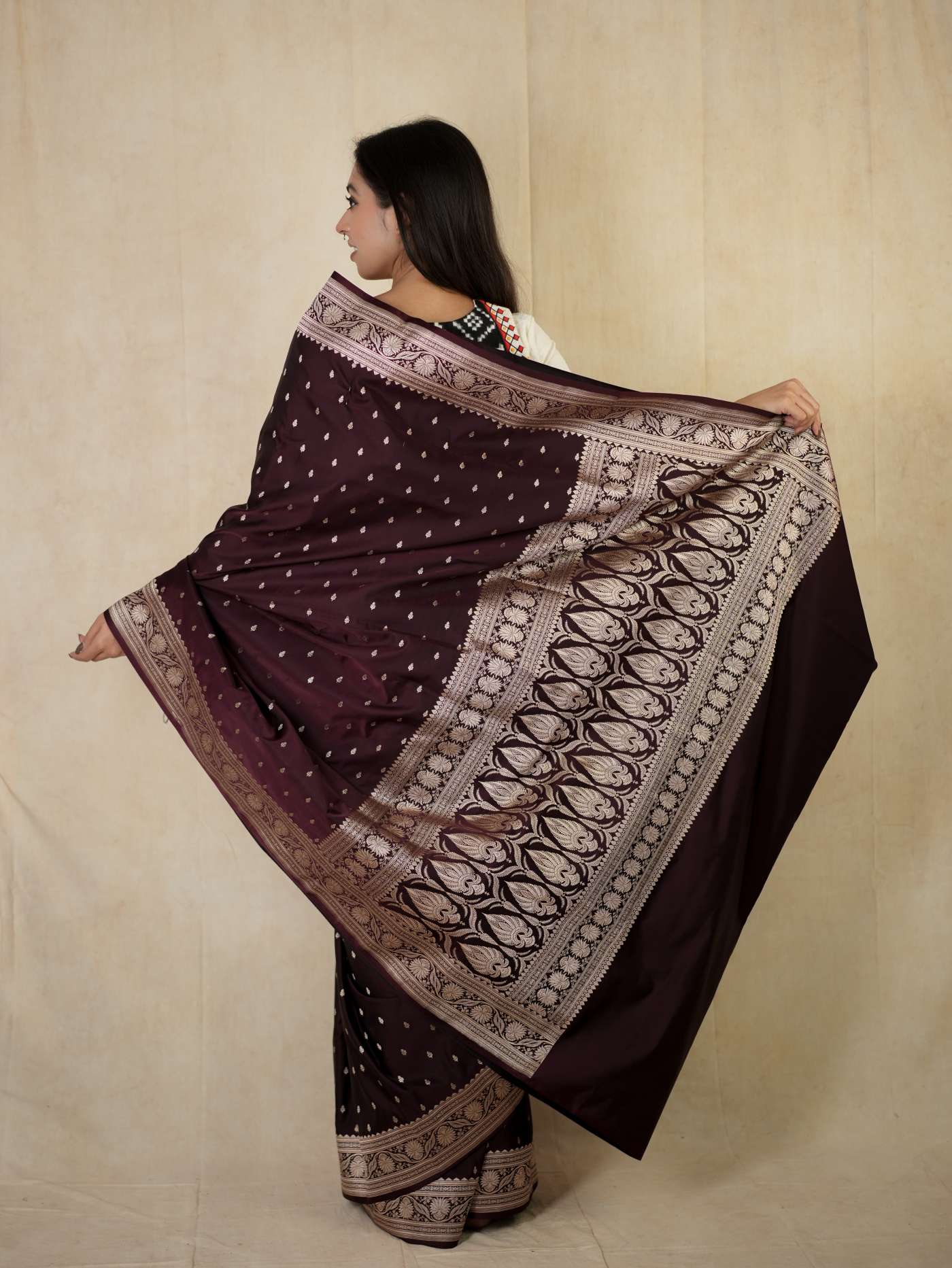 Dark brown Benarasi semi-silk saree with intricate patterns and matching blouse piece, showcased on a hanger.