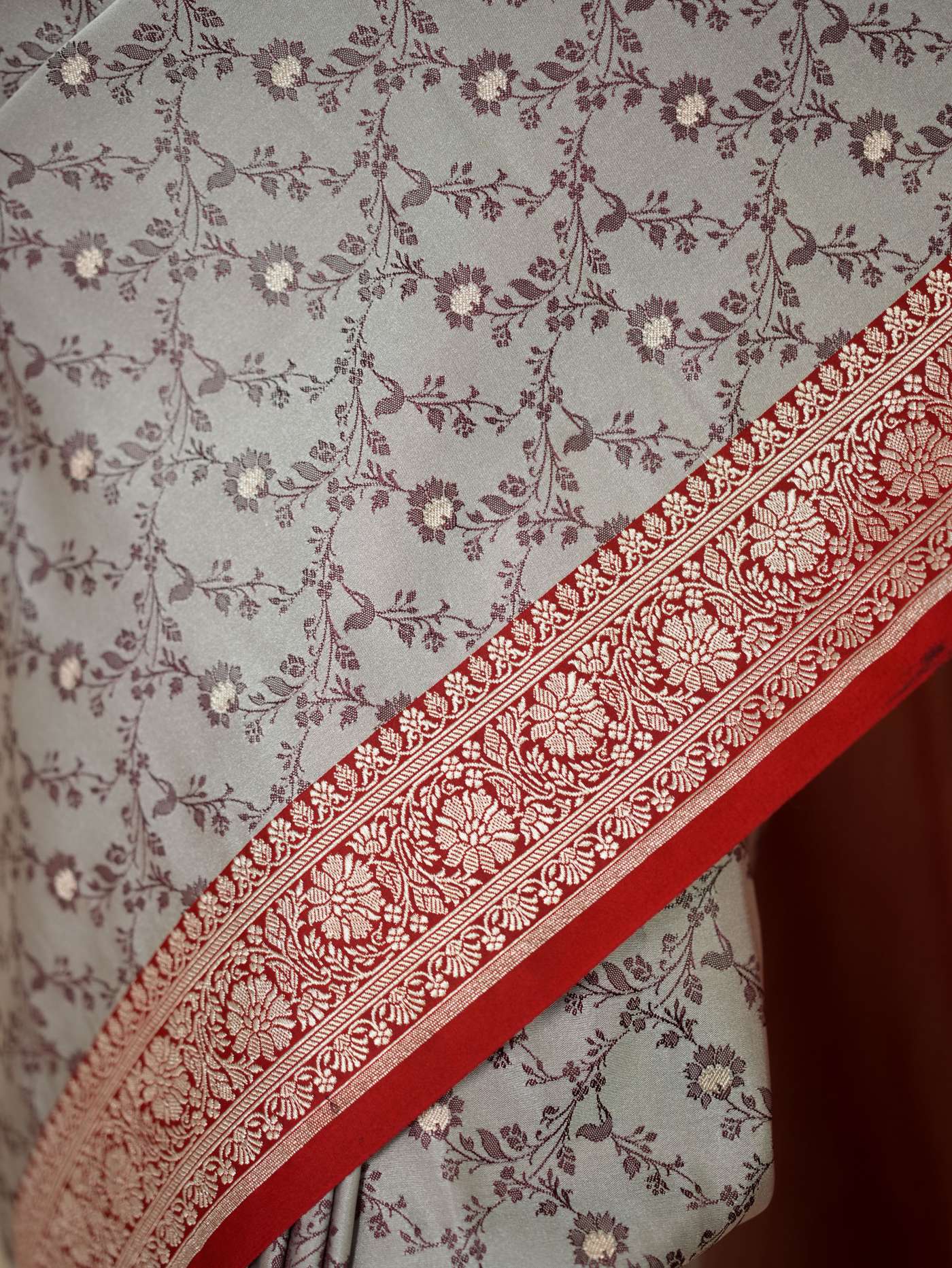 Grey semi Benarasi silk saree with intricate patterns and matching blouse piece, crafted by Joyee Kolkata.