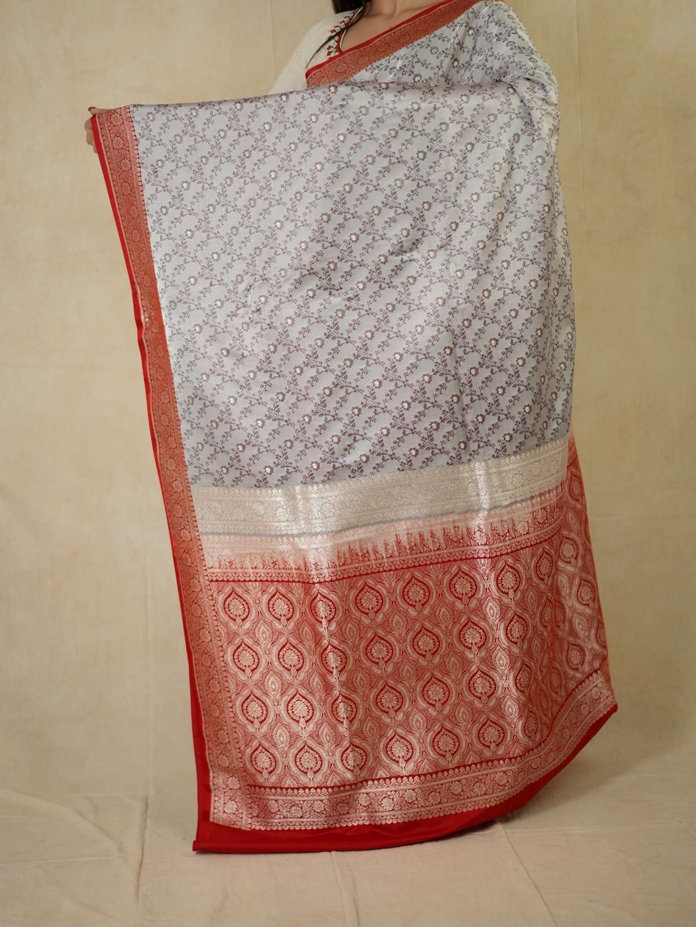 Grey semi-Benarasii silk saree with intricate designs and matching blouse piece from Joyee Kolkata, displayed in the image.