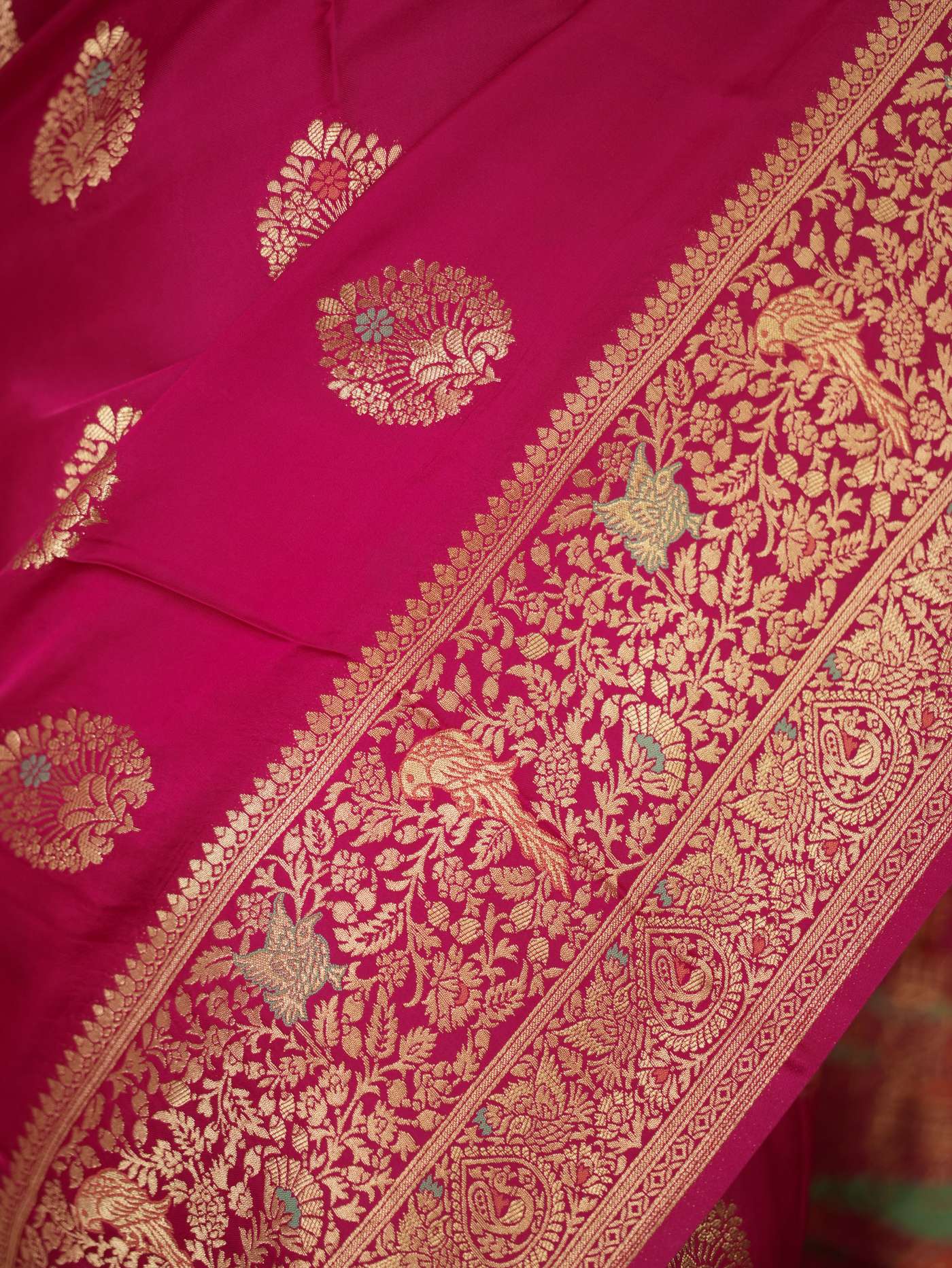 Magenta semi-silk Benarasi saree with intricate patterns and a matching blouse piece, styled for traditional Indian wear.