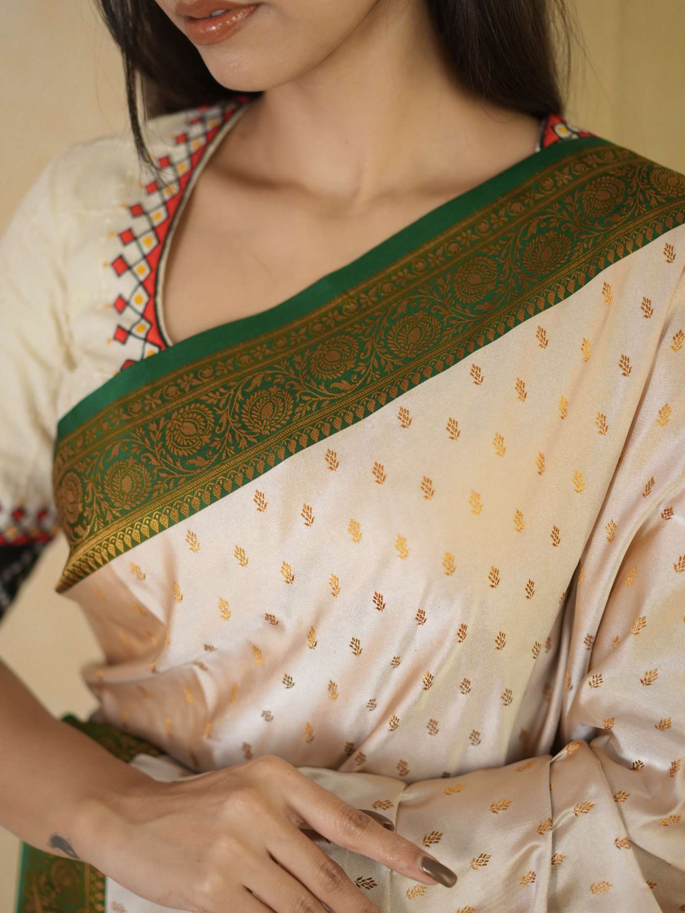 Cream semi Benarasi silk saree by Joyee Kolkata with intricate patterns and matching 88 cm blouse piece, displayed on a hanger.