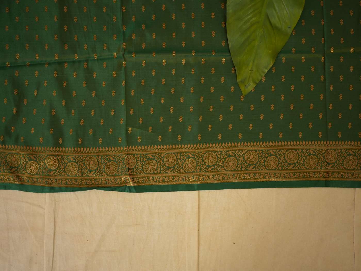 Cream semi-Benarasi silk saree by Joyee Kolkata with intricate weaving, paired with an 88 cm blouse piece, displayed on a hanger.