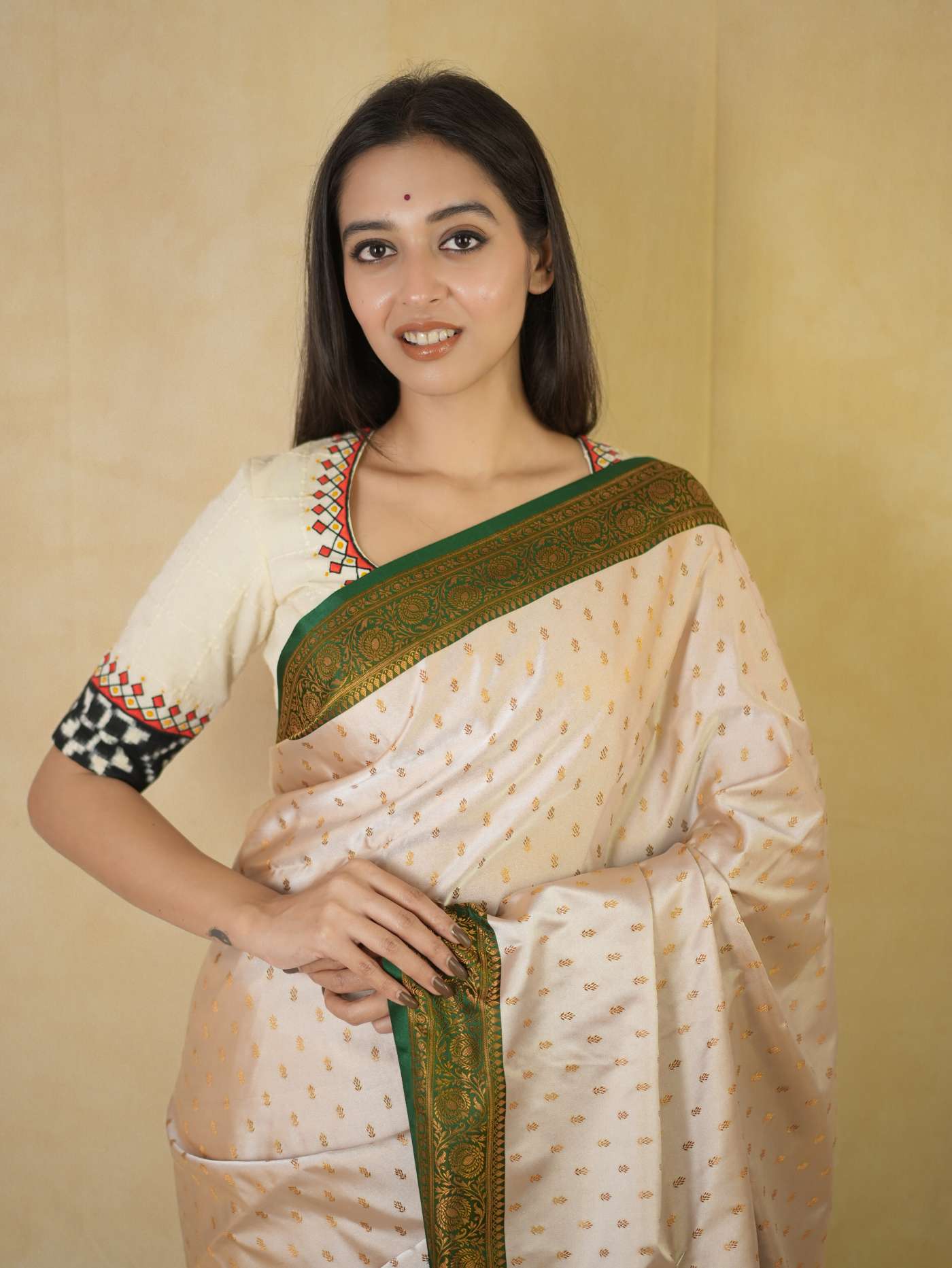 Cream semi Benarasi silk saree with intricate designs and matching 88 cm blouse piece from Joyee Kolkata, displayed on a hanger.