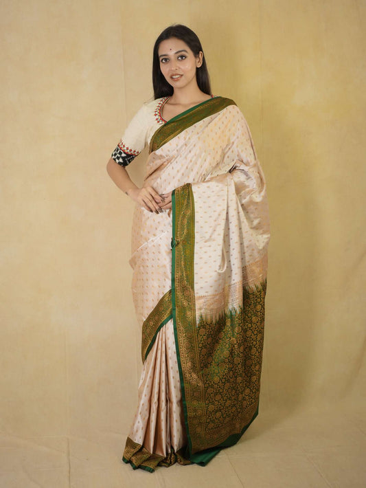 Cream semi Benarasi silk saree by Joyee Kolkata with intricate designs and 88 cm matching blouse piece displayed on a mannequin.