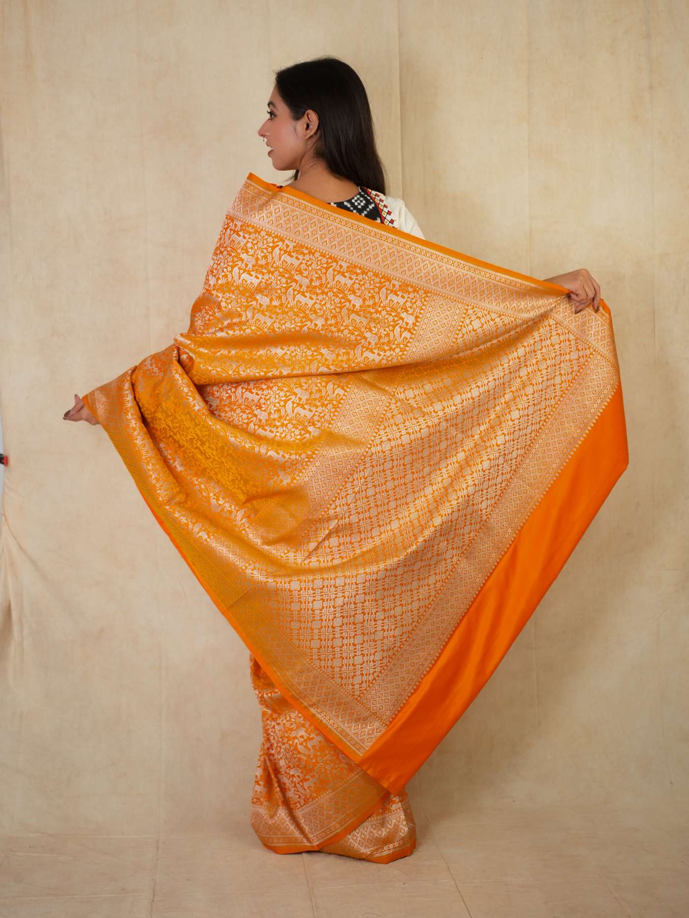 Orange semi Benarasi silk saree with intricate designs and matching blouse piece from Joyee Kolkata, displayed on a mannequin.