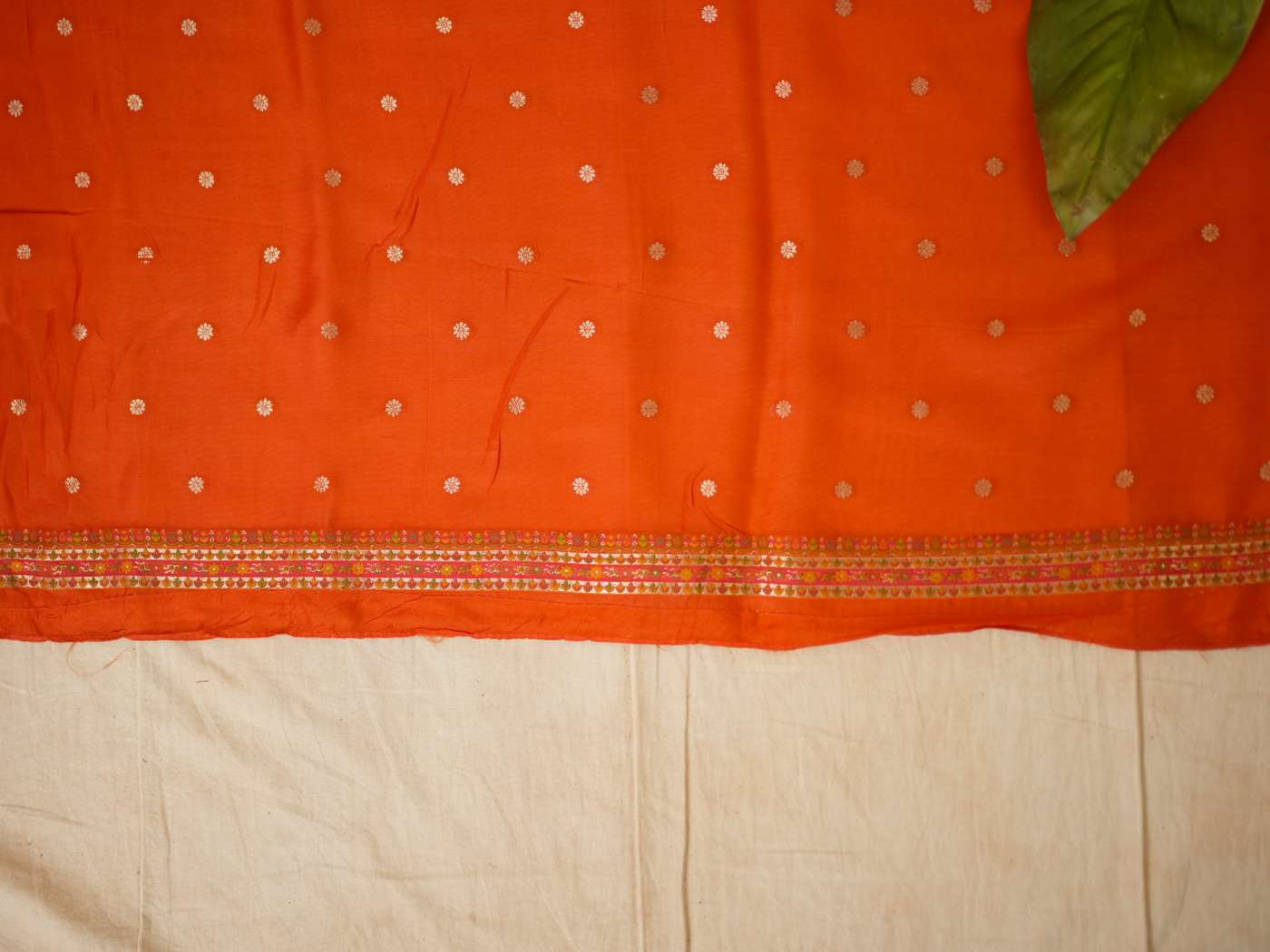 Reddish orange semi Benarasi silk saree by Joyee Kolkata with matching blouse piece, intricate weaving and traditional design.