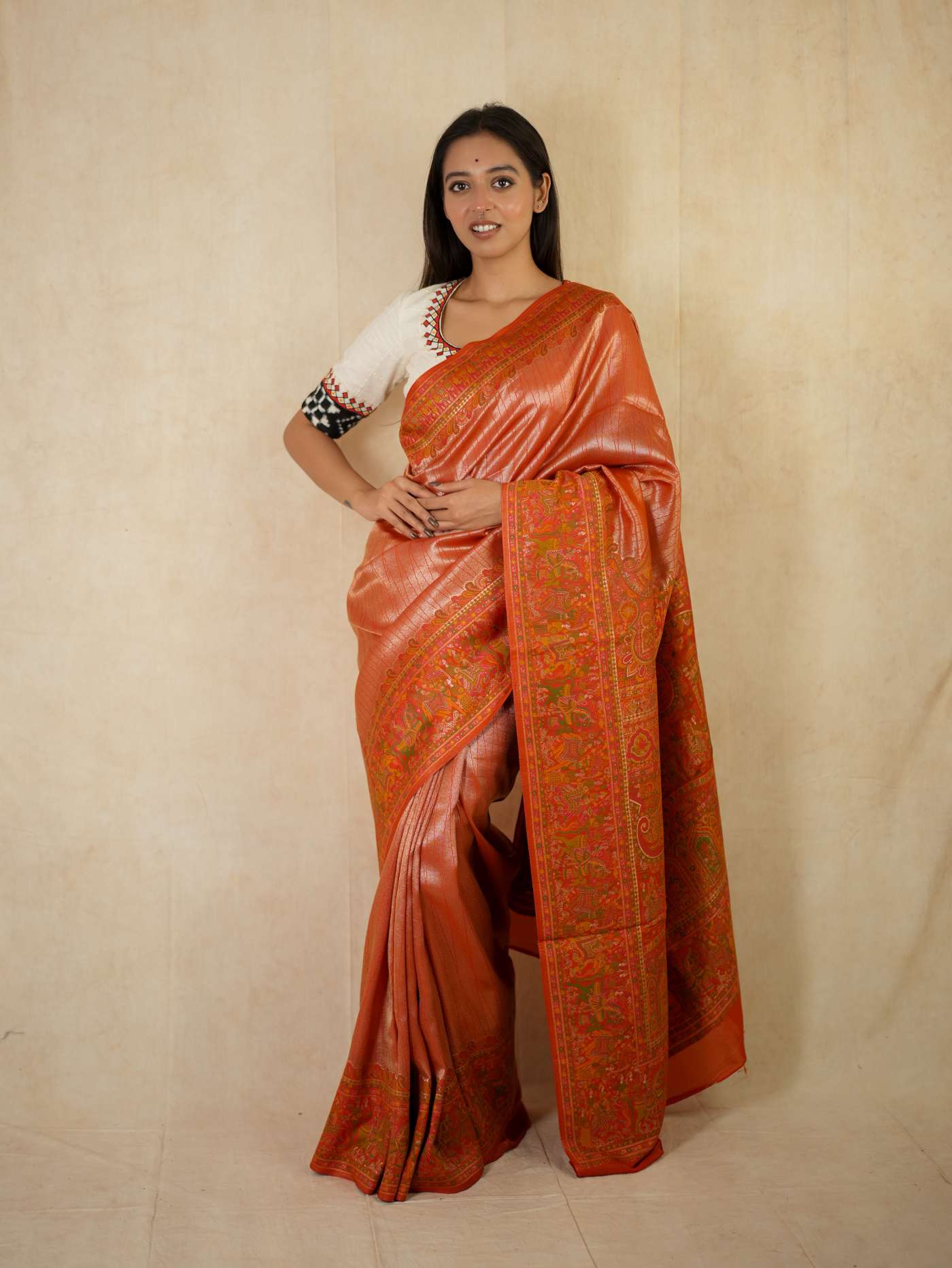 Reddish orange semi Benarasi silk saree with intricate designs, paired with a 1-meter matching blouse piece, by Joyee Kolkata.