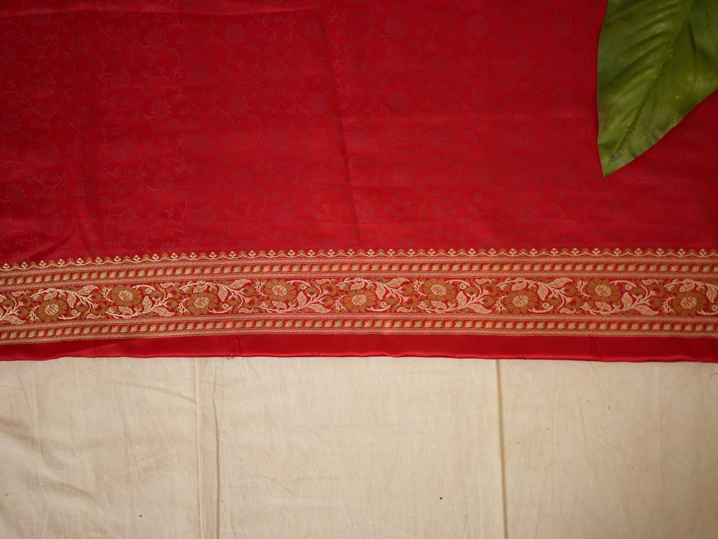 Rich red Benarasi semi-silk saree with intricate gold zari work and matching blouse piece, crafted by Joyee Kolkata.