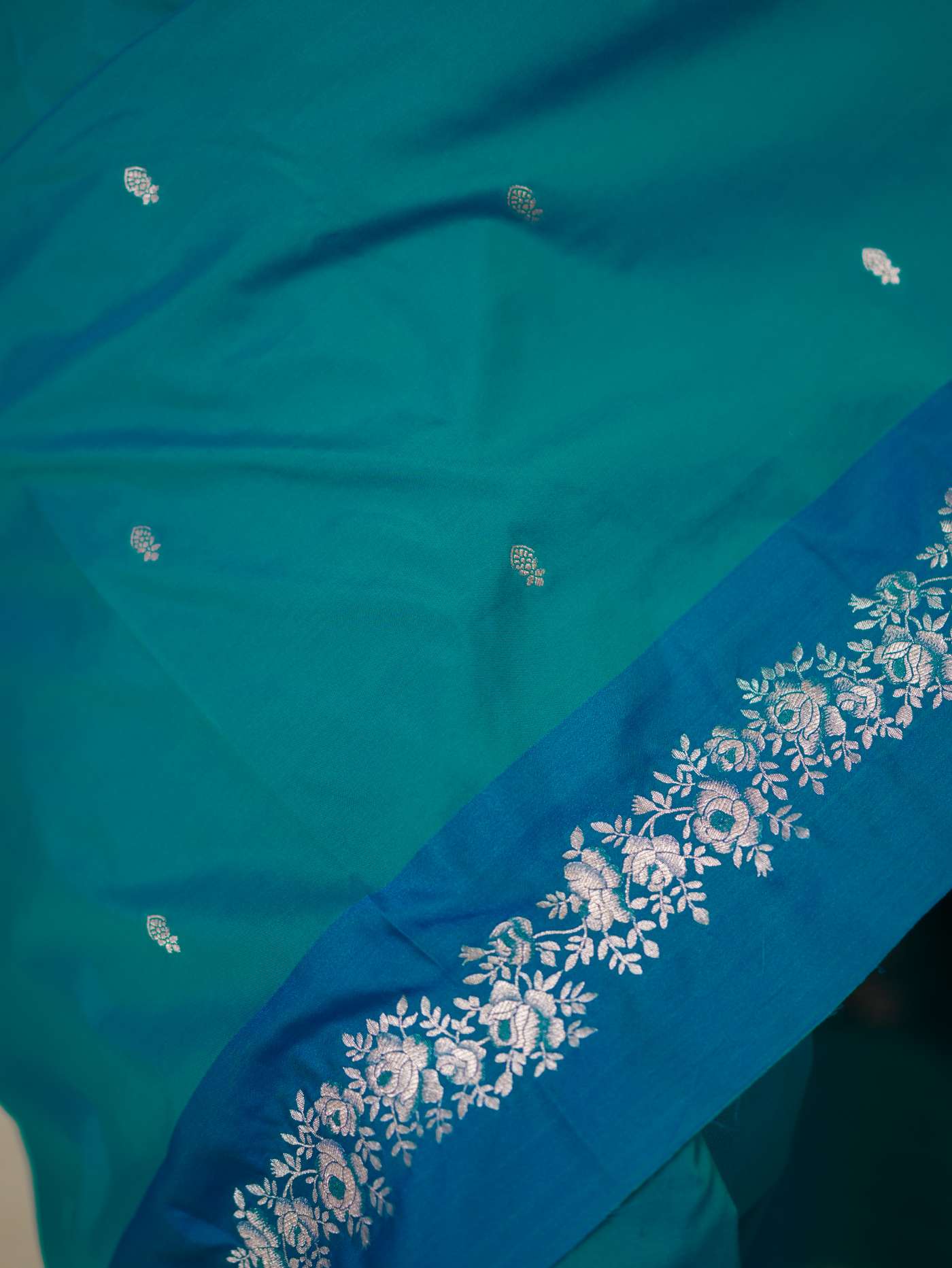 Turquoise blue semi-silk Benarasi saree with intricate patterns and matching blouse piece from Joyee Kolkata.