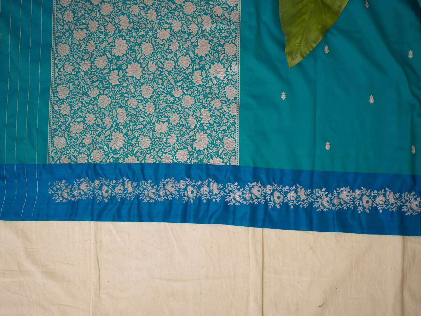 Turquoise blue semi-silk Benarasi saree with intricate patterns, paired with a 1-meter blouse piece from Joyee Kolkata.