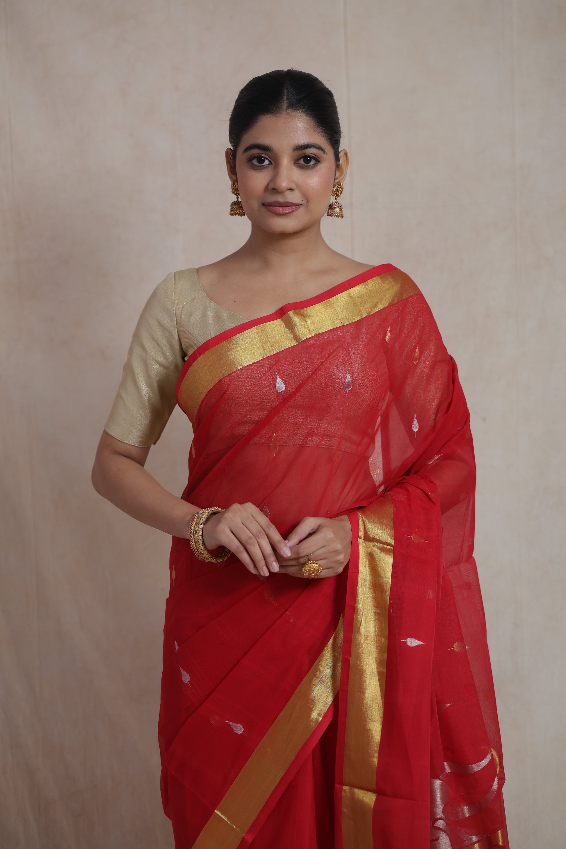 Model wearing red Kanchipuram cotton saree with gold woven border