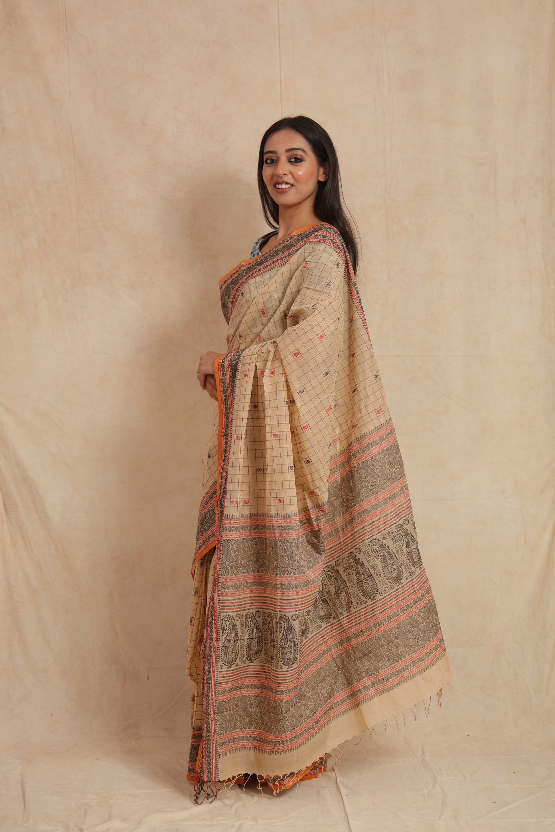 Side profile of beige Kanchipuram cotton saree featuring paisley woven pallu and border
