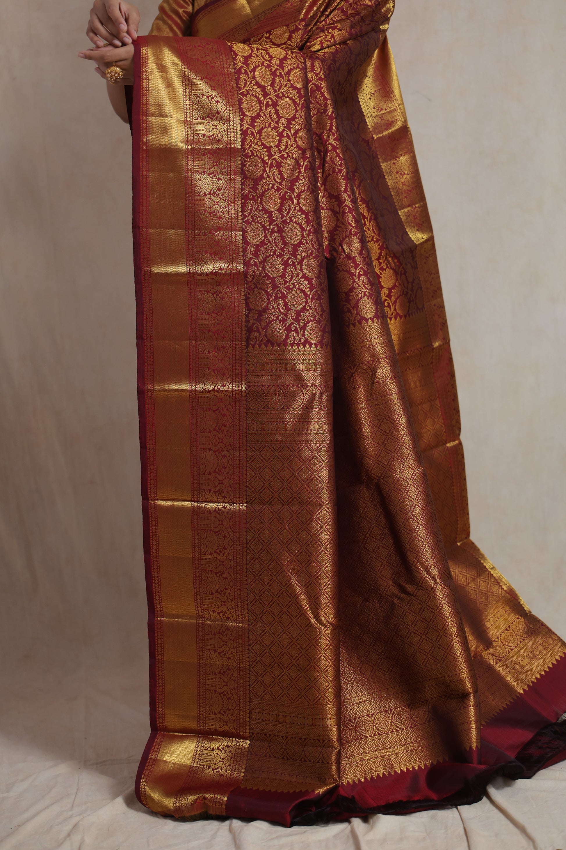 Detailed close-up of golden zari woven pallu on maroon Kanjivaram silk saree