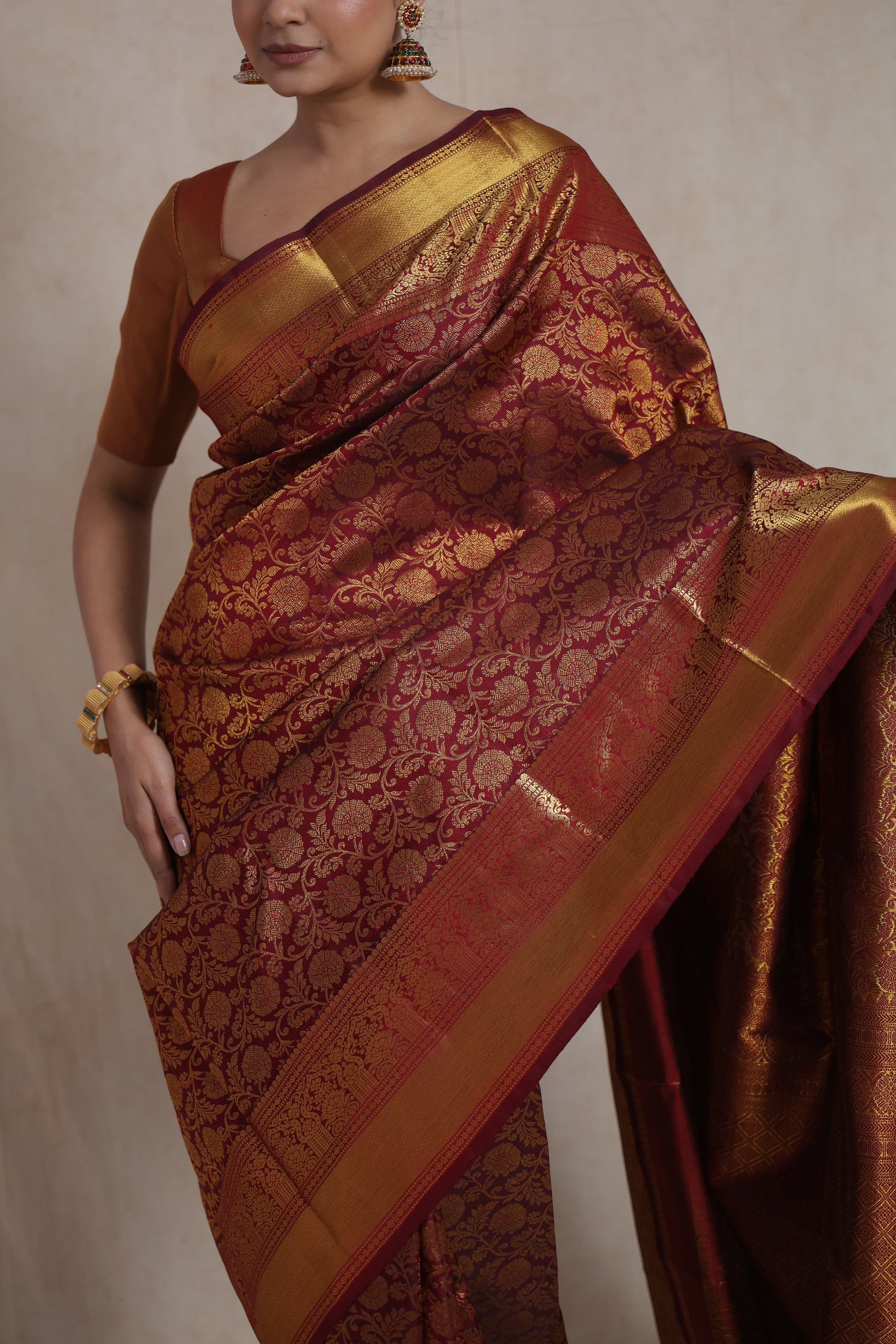 Close-up of maroon Kanjivaram silk saree with intricate golden floral zari weaving