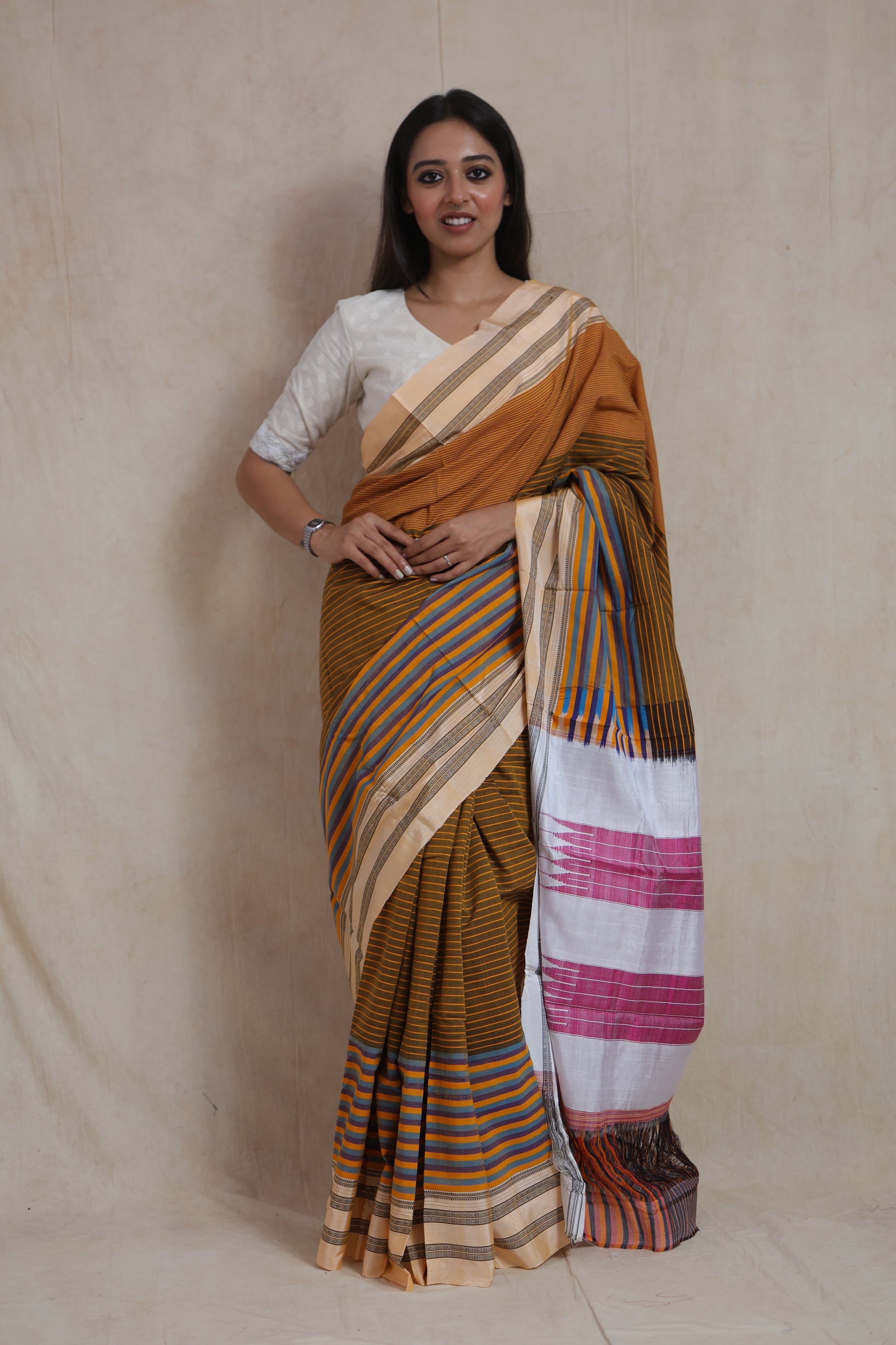 Front view of mustard brown Ilkal handloom cotton saree with multicolor striped pallu and traditional border