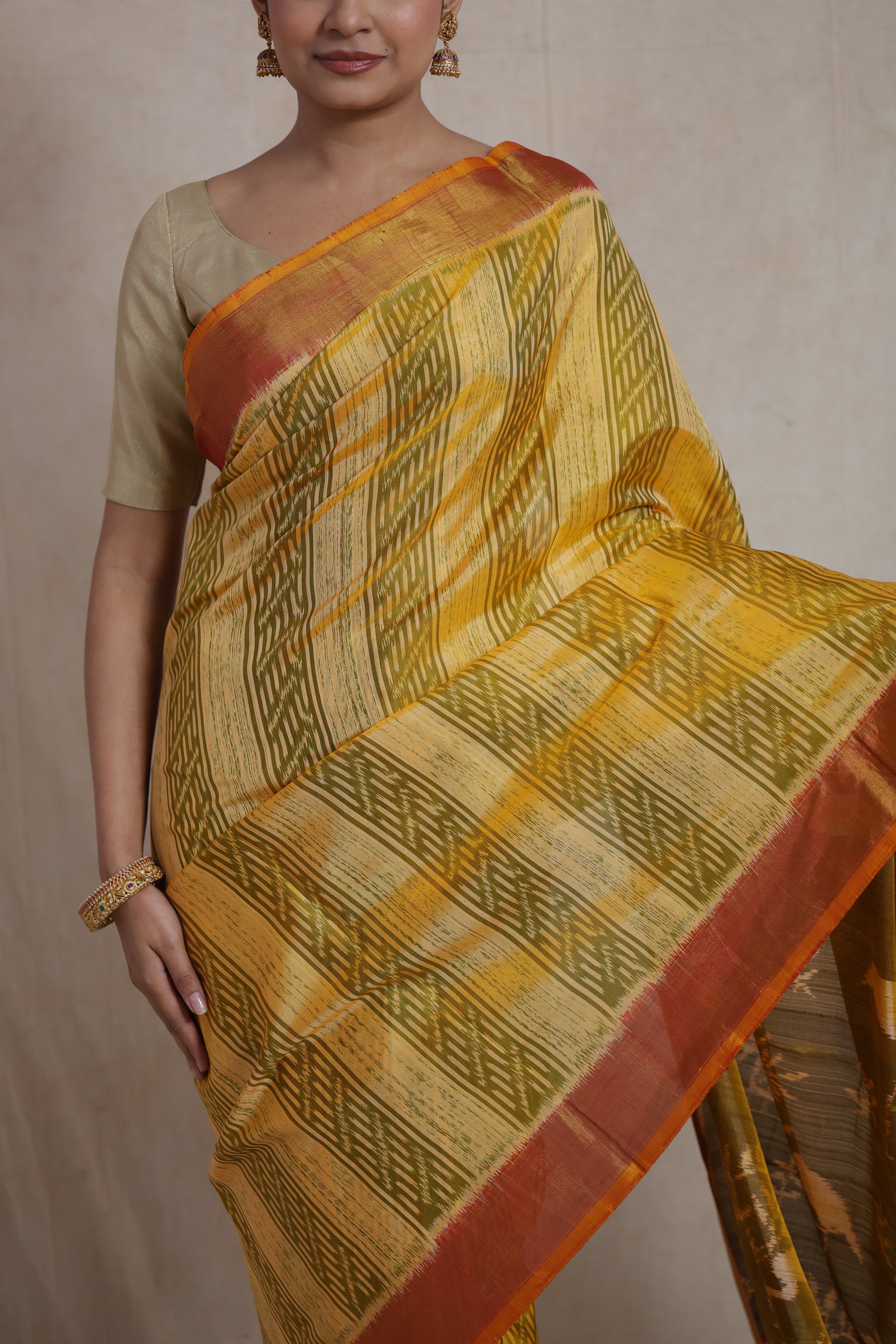 Drape detail of mustard yellow Patola silk saree with olive green woven design