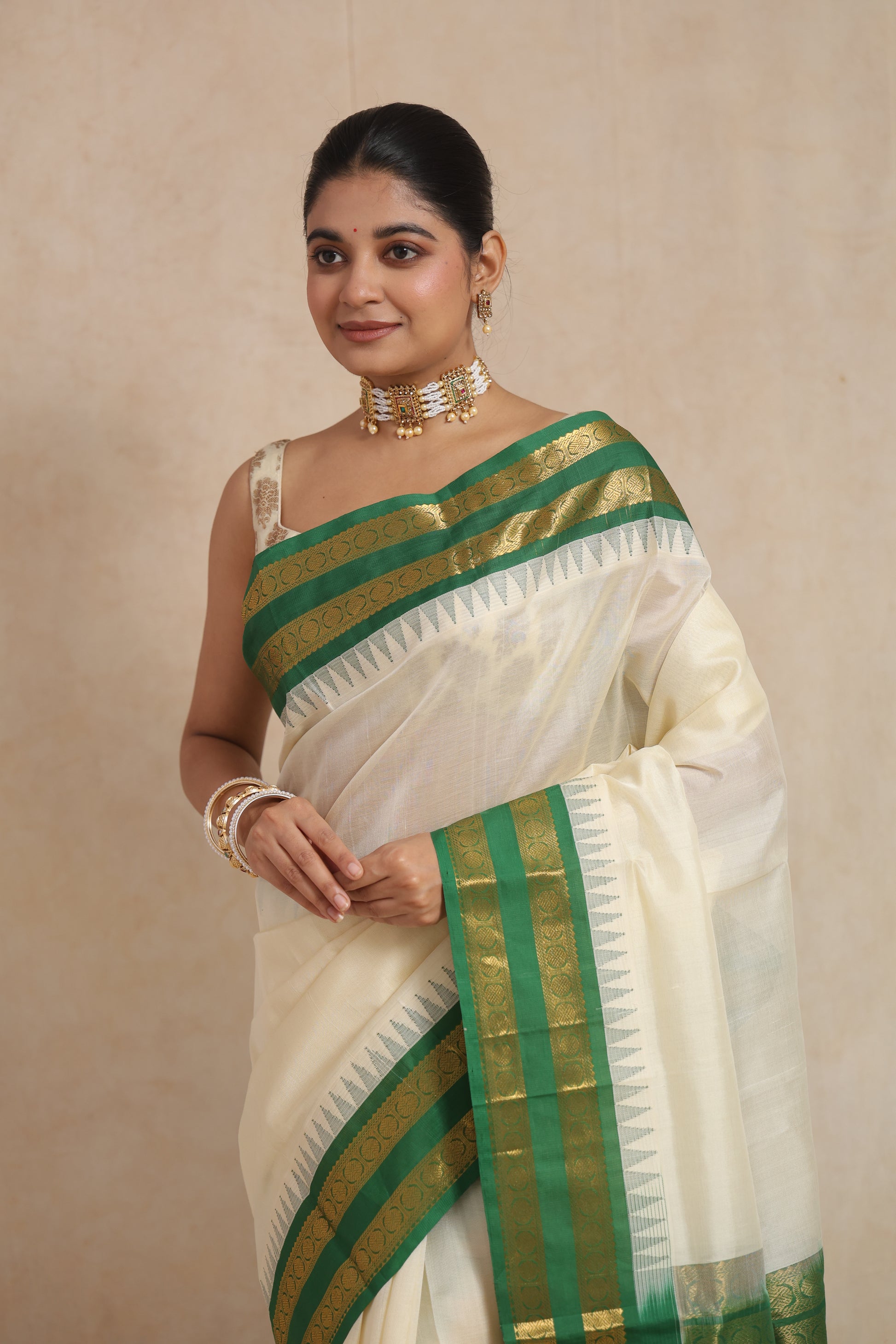 Portrait view of model wearing off-white Kanchipuram Sico saree with green border