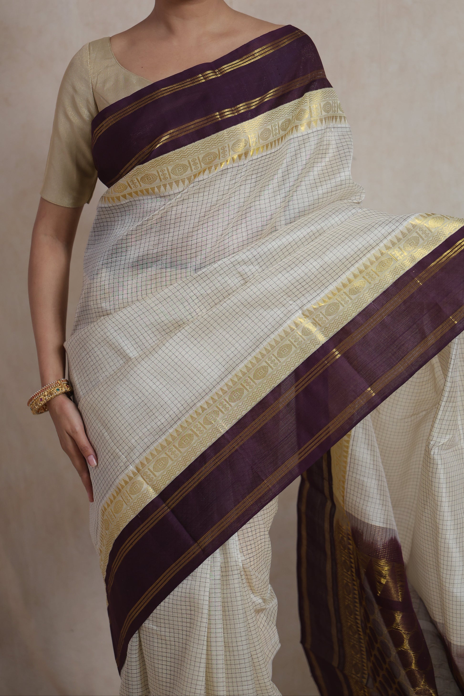 Front drape view of off white Kanchipuram Sico saree with purple border
