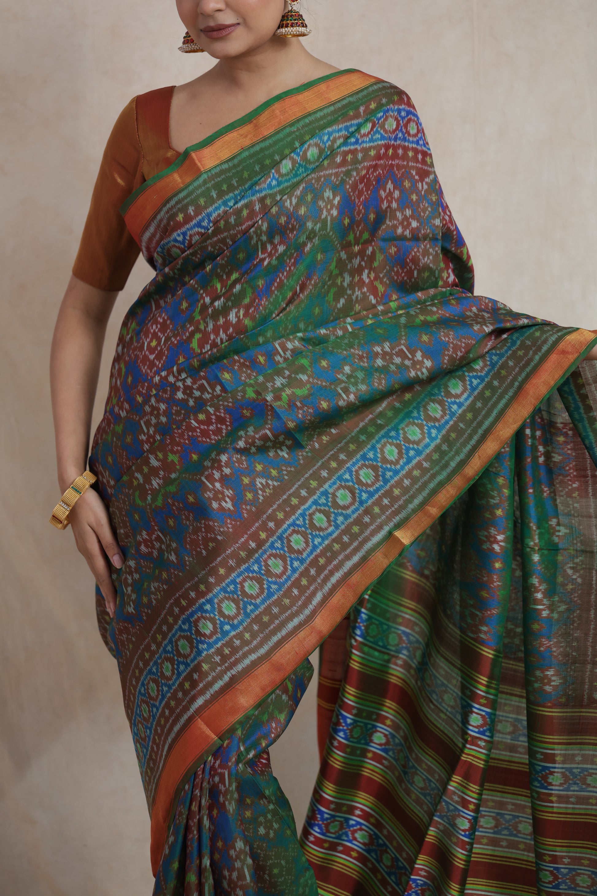 Detailed drape of olive green Patola silk saree featuring vibrant blue and copper woven designs