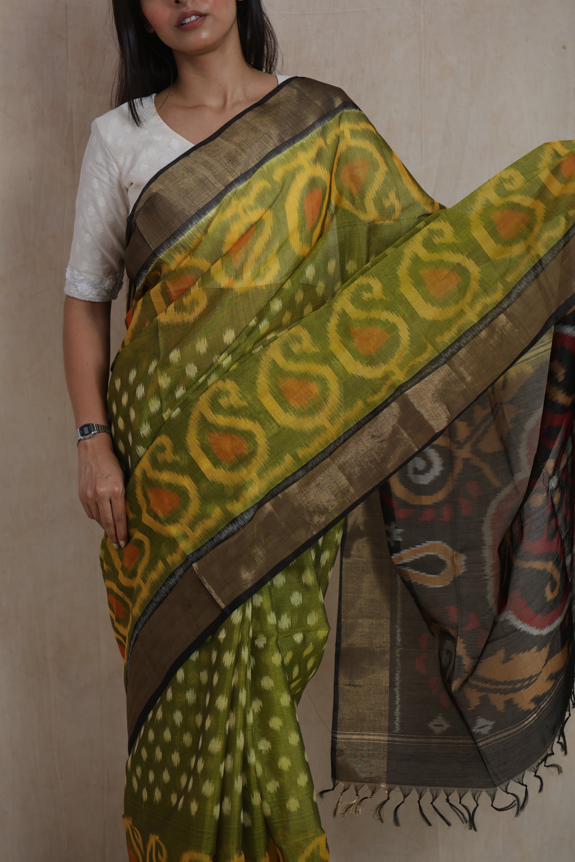 Close-up of olive green Pochampally silk cotton saree showcasing intricate Ikat motifs and zari detailing