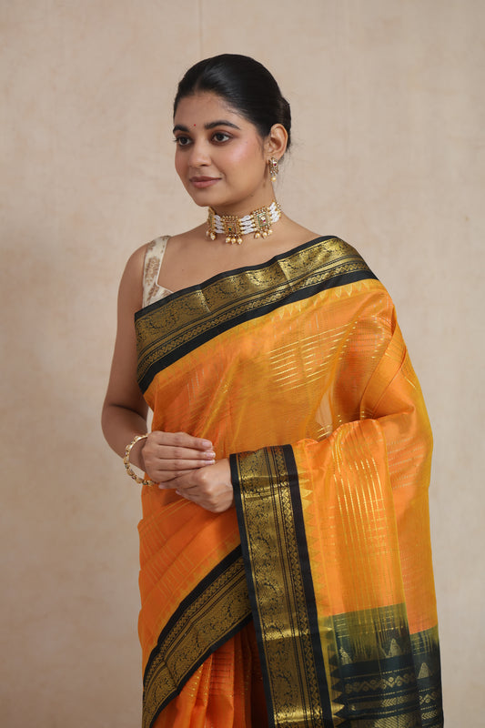 Portrait view of model wearing orange Kanchipuram Sico saree with zari border