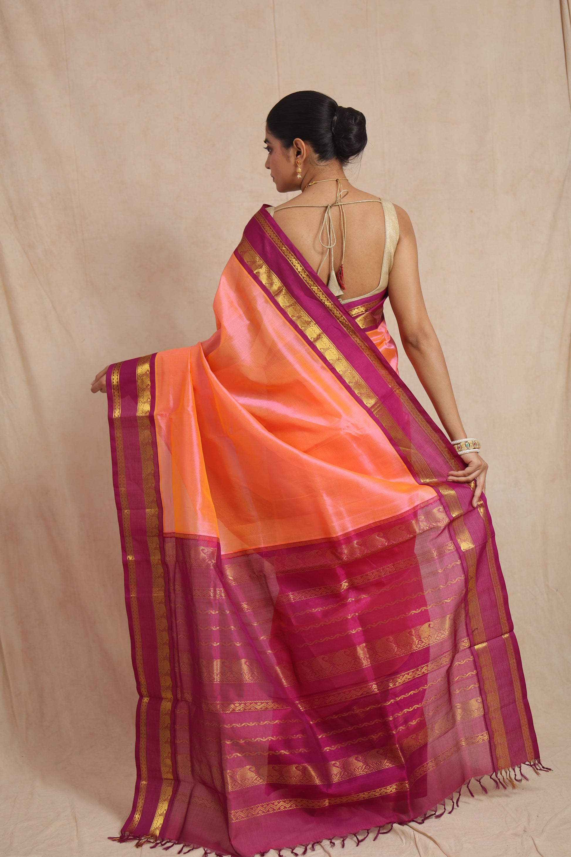Styled pose of pink Kanchipuram silk cotton saree with contrast black pallu