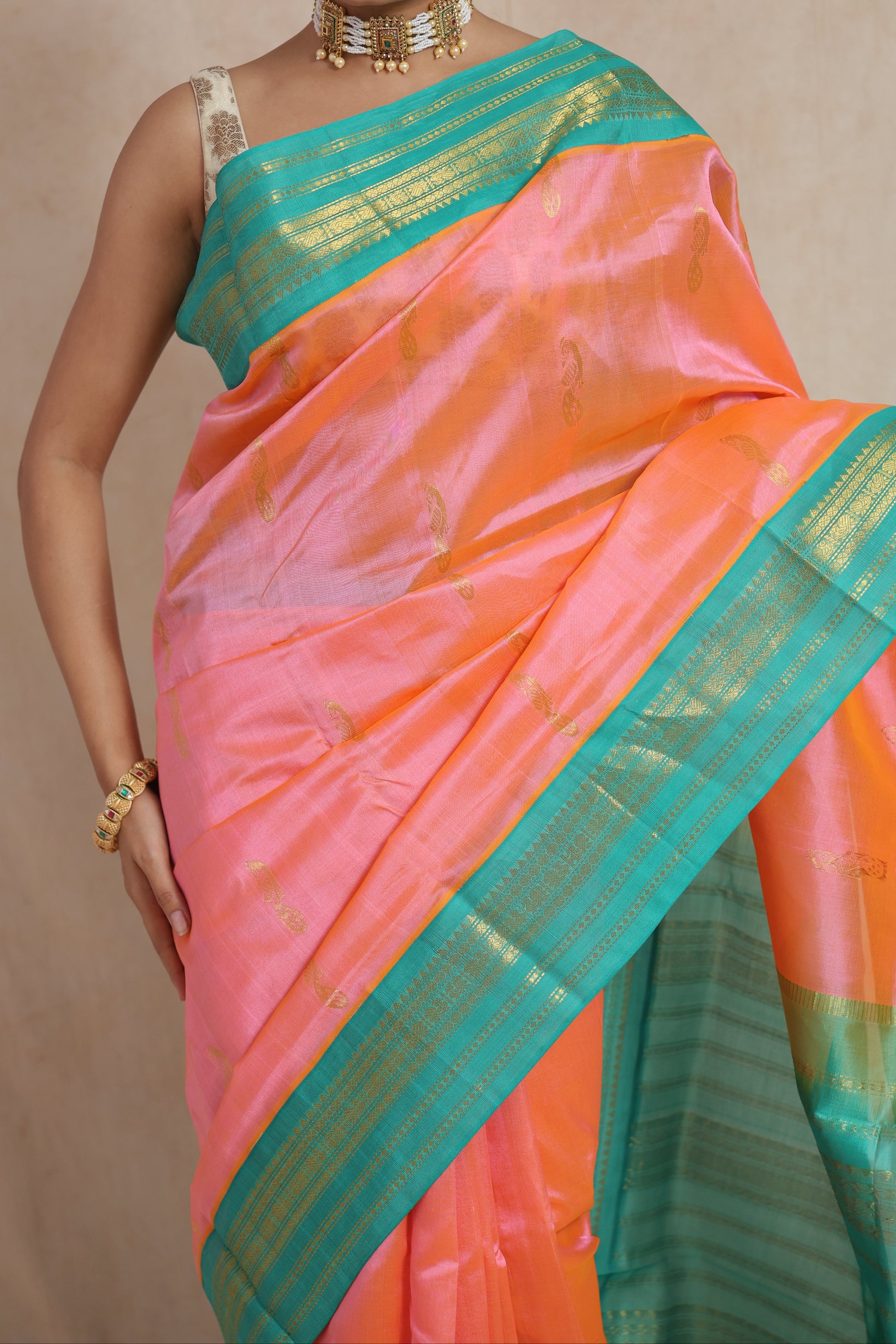 Close-up of peach pink Kanchipuram Sico saree with aqua blue woven border and buttas