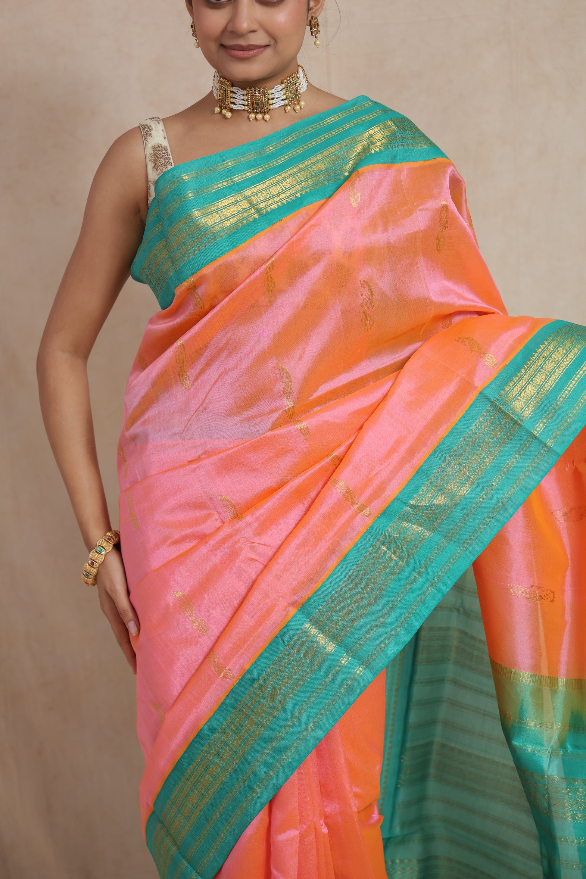 Close-up of peach pink Kanchipuram Sico saree with traditional woven motifs and blue border
