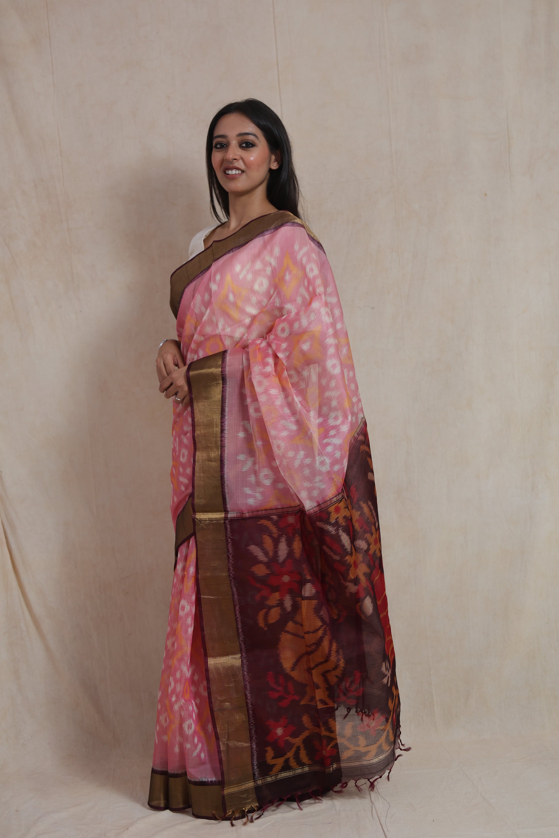 Side profile of blush pink Panchampali silk cotton saree featuring traditional Ikat patterns and floral pallu