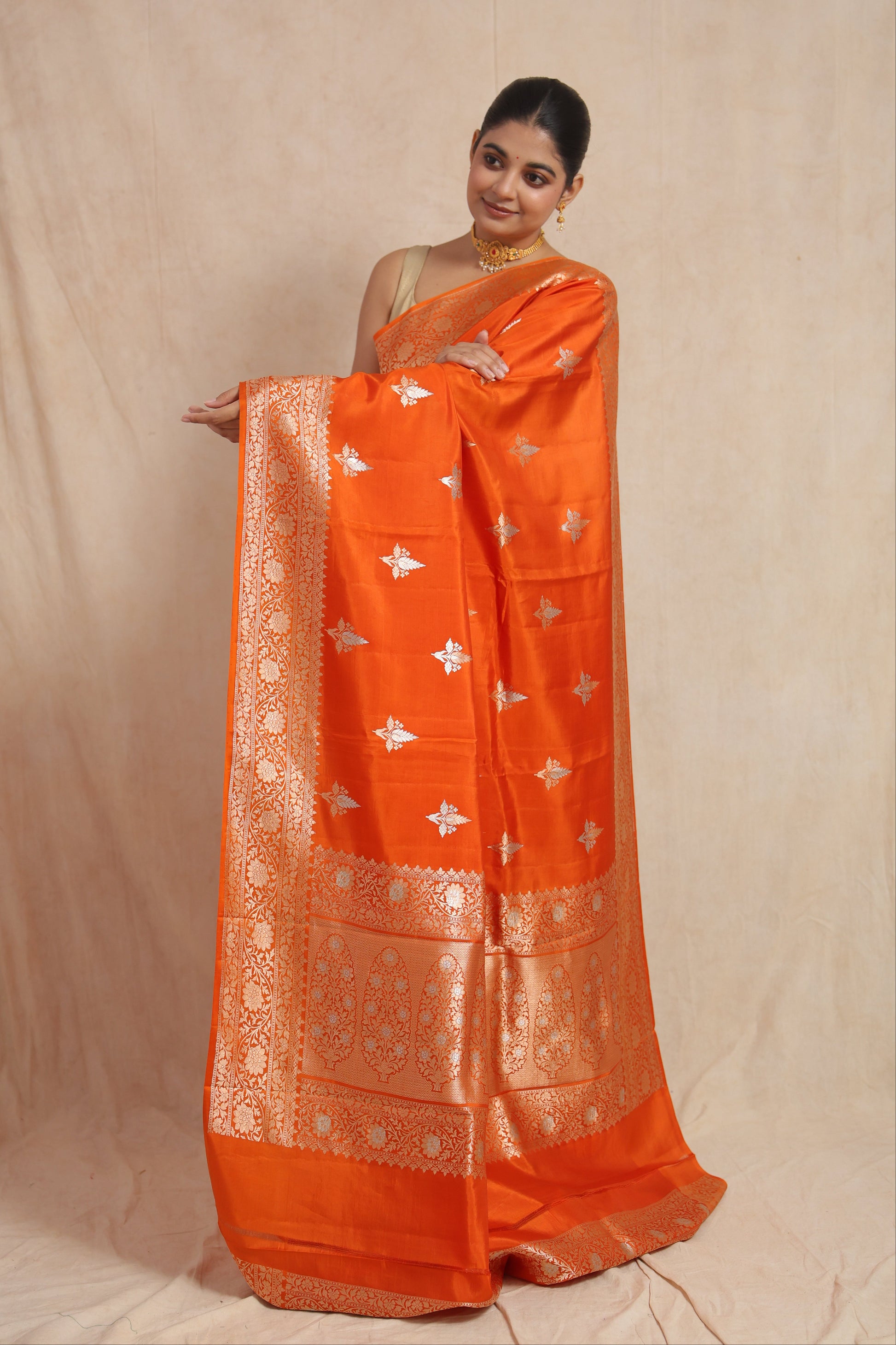 Full pallu display of orange Banarasi silk saree with ornate floral weaving and traditional border