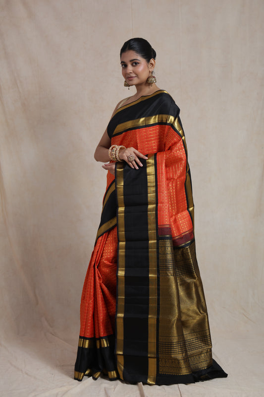 Side drape view of vermilion red Kanjivaram silk saree with black border and rich pallu